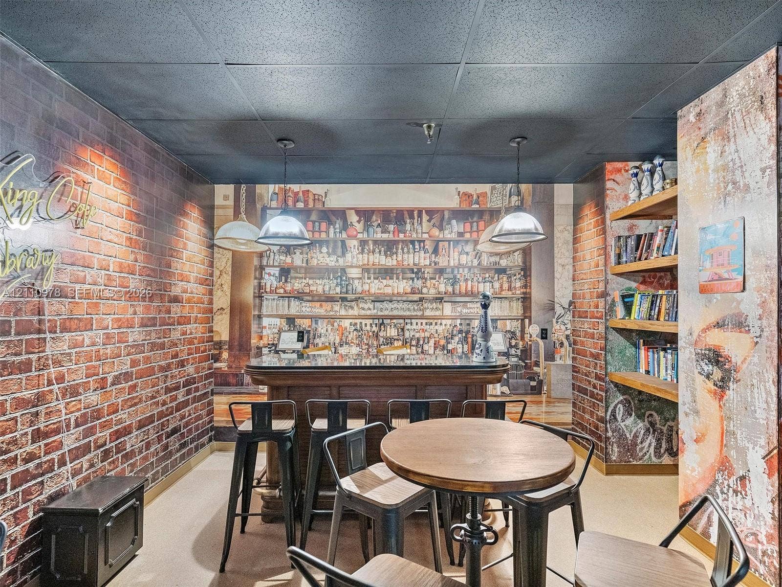 900 Bay Drive, #225, Miami Beach, FL 33141 Built-in bar featuring a stone-finish countertop, pendant lighting, textured brick-style walls, and integrated wood shelving