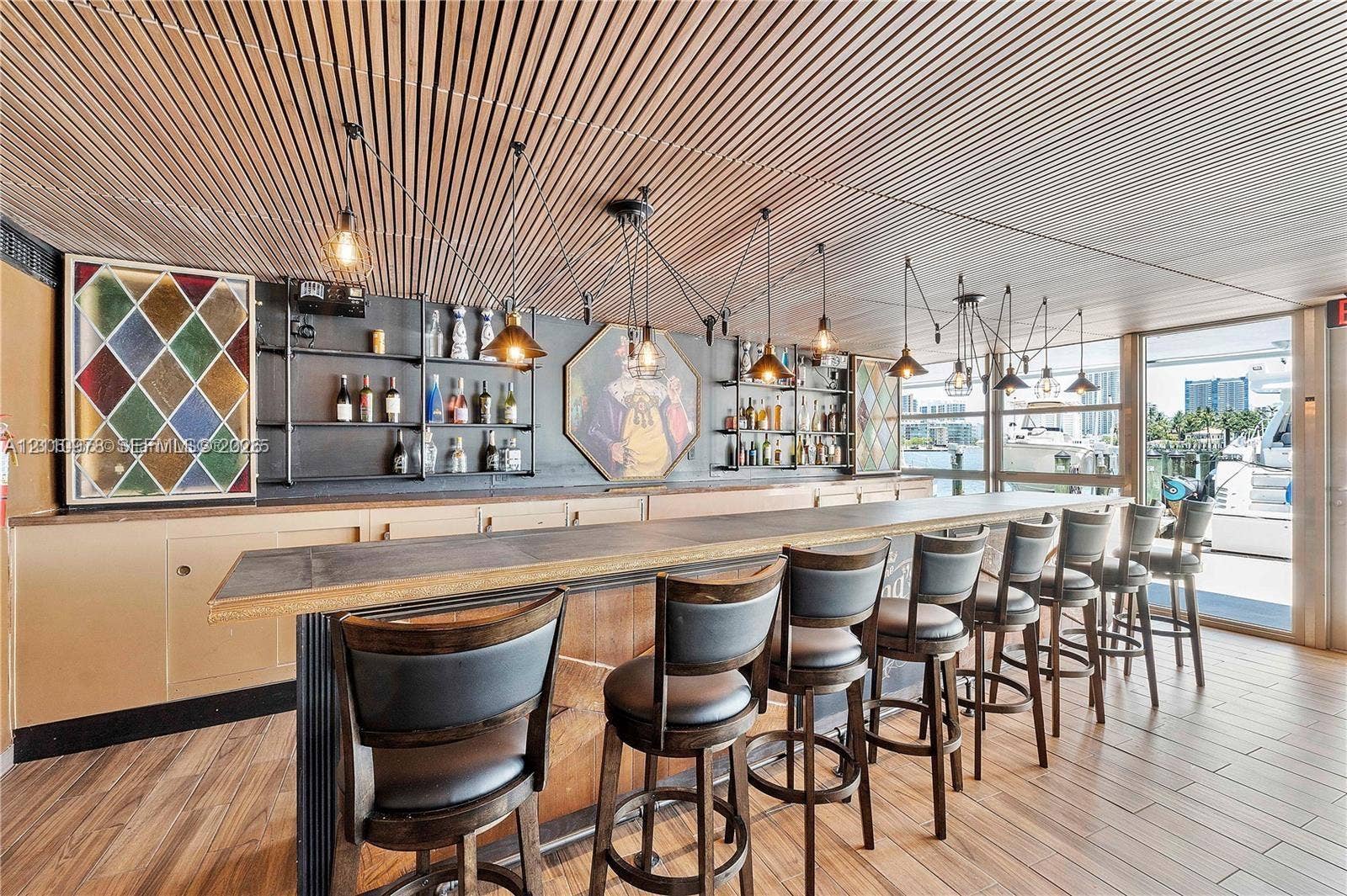 900 Bay Drive, #225, Miami Beach, FL 33141 Built-in bar featuring a linear stone-finish countertop, wood-finish flooring, slatted wood ceiling, and black metal open-shelving cabinetry
