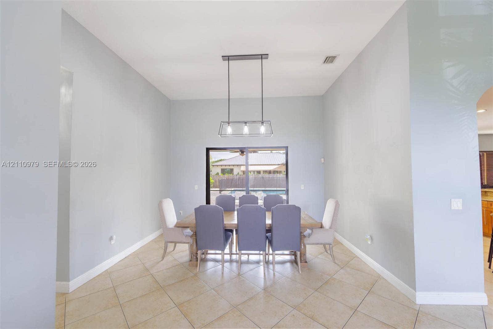 High ceilings featuring a linear pendant light fixture, ceramic tile flooring, and a sliding glass door