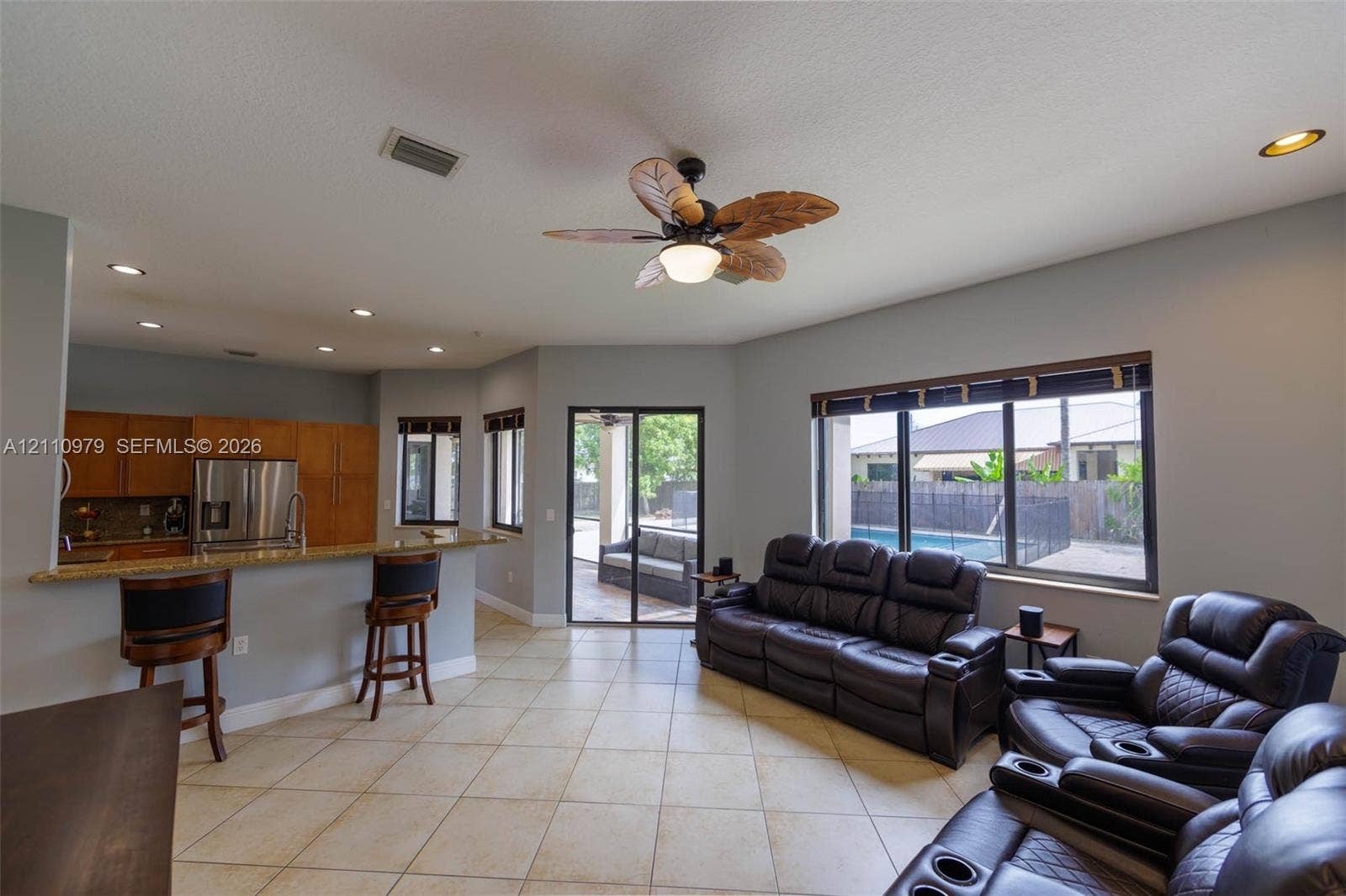 Open-concept living space featuring ceramic tile flooring, recessed lighting, and a kitchen breakfast bar with stone countertops