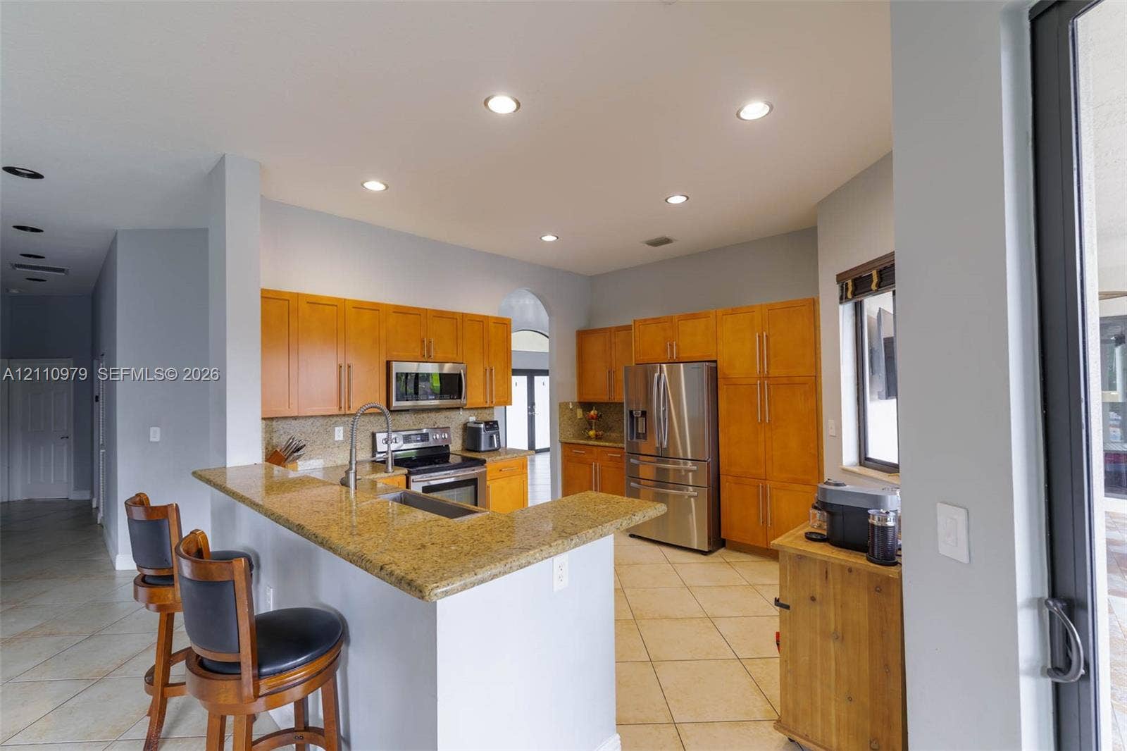 Kitchen featuring wood cabinetry, stone countertops, breakfast bar, recessed lighting, and stainless steel appliances