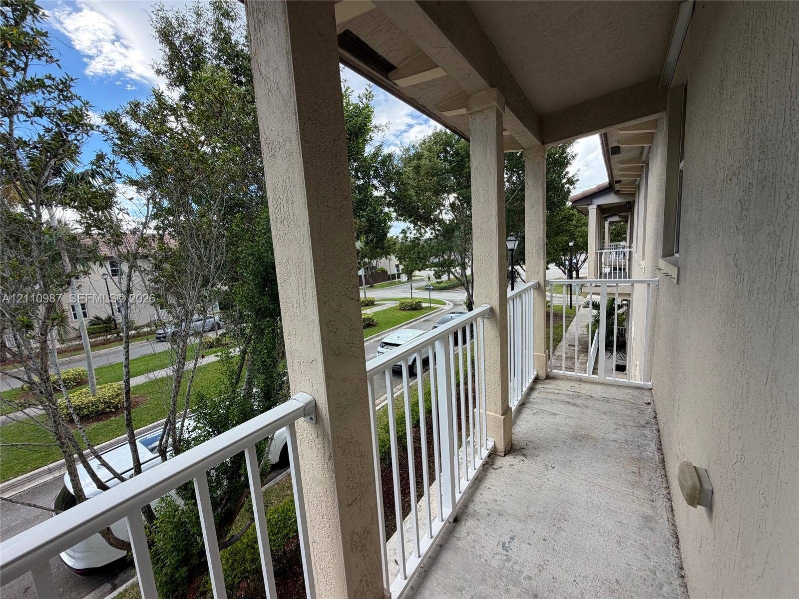 Covered balcony featuring stucco support columns and white metal railings