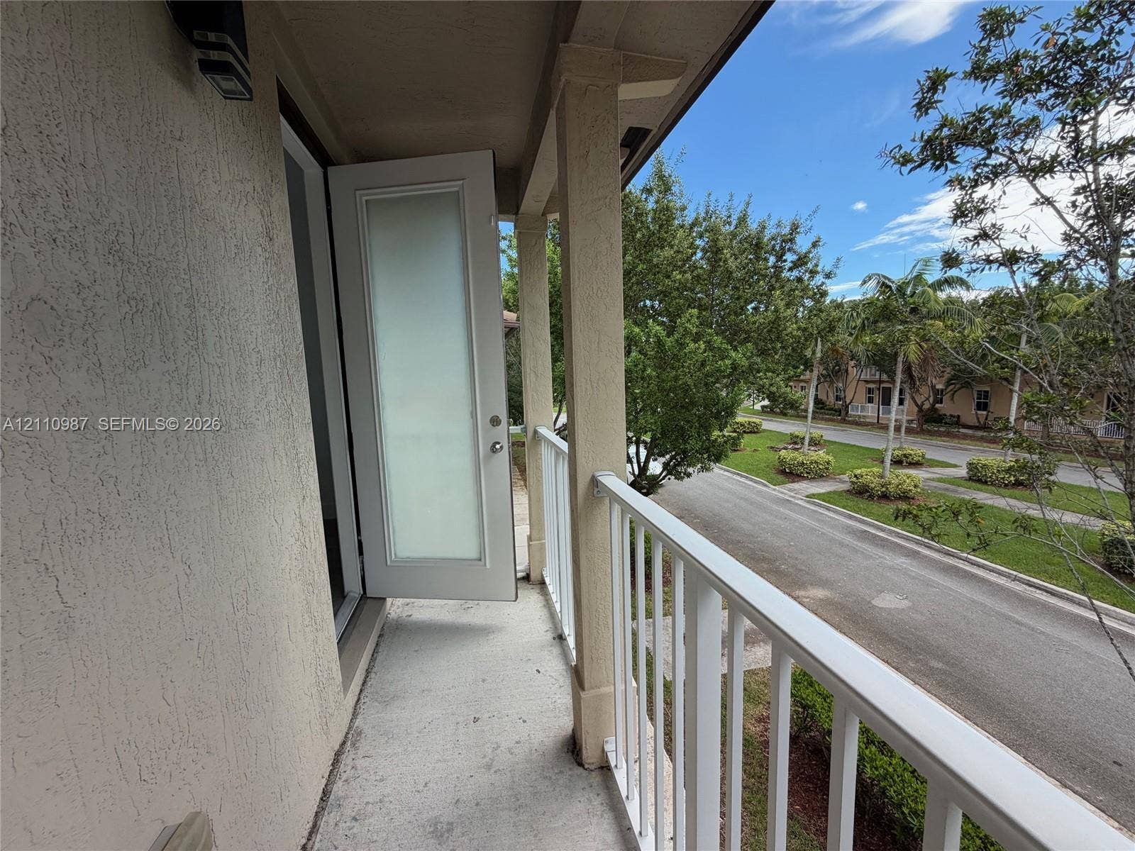 Covered exterior balcony featuring a stucco finish, structural support columns, and white metal railing