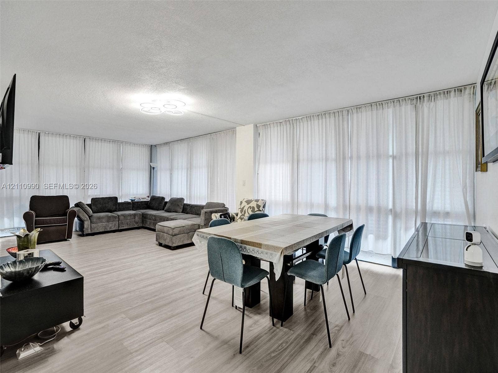 800 Parkview Drive, #131, Hallandale Beach, FL 33009 Open-concept living space featuring wood-finish flooring, floor-to-ceiling windows with window treatments, and an attached decorative ceiling light fixture
