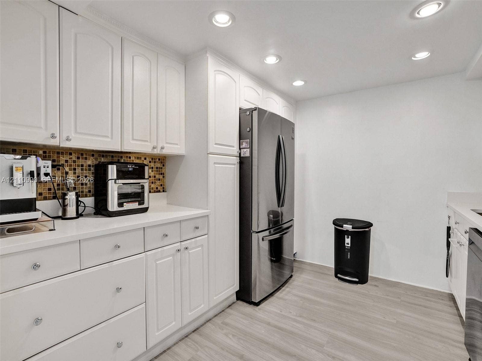 800 Parkview Drive, #131, Hallandale Beach, FL 33009 Kitchen featuring white cabinetry, light-toned countertops, a mosaic tile backsplash, recessed lighting, and stainless steel appliances