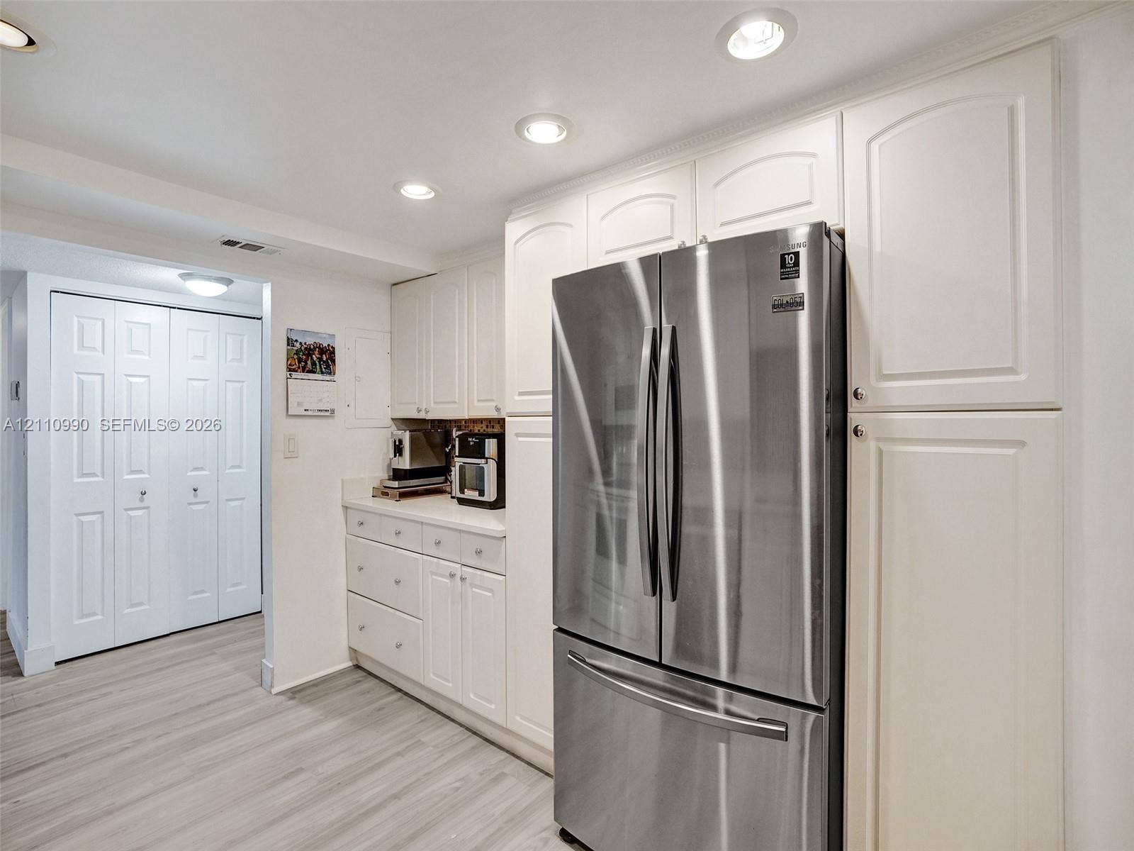 800 Parkview Drive, #131, Hallandale Beach, FL 33009 Kitchen featuring white shaker-style cabinetry, stainless steel refrigerator, recessed lighting, and wood-finish flooring