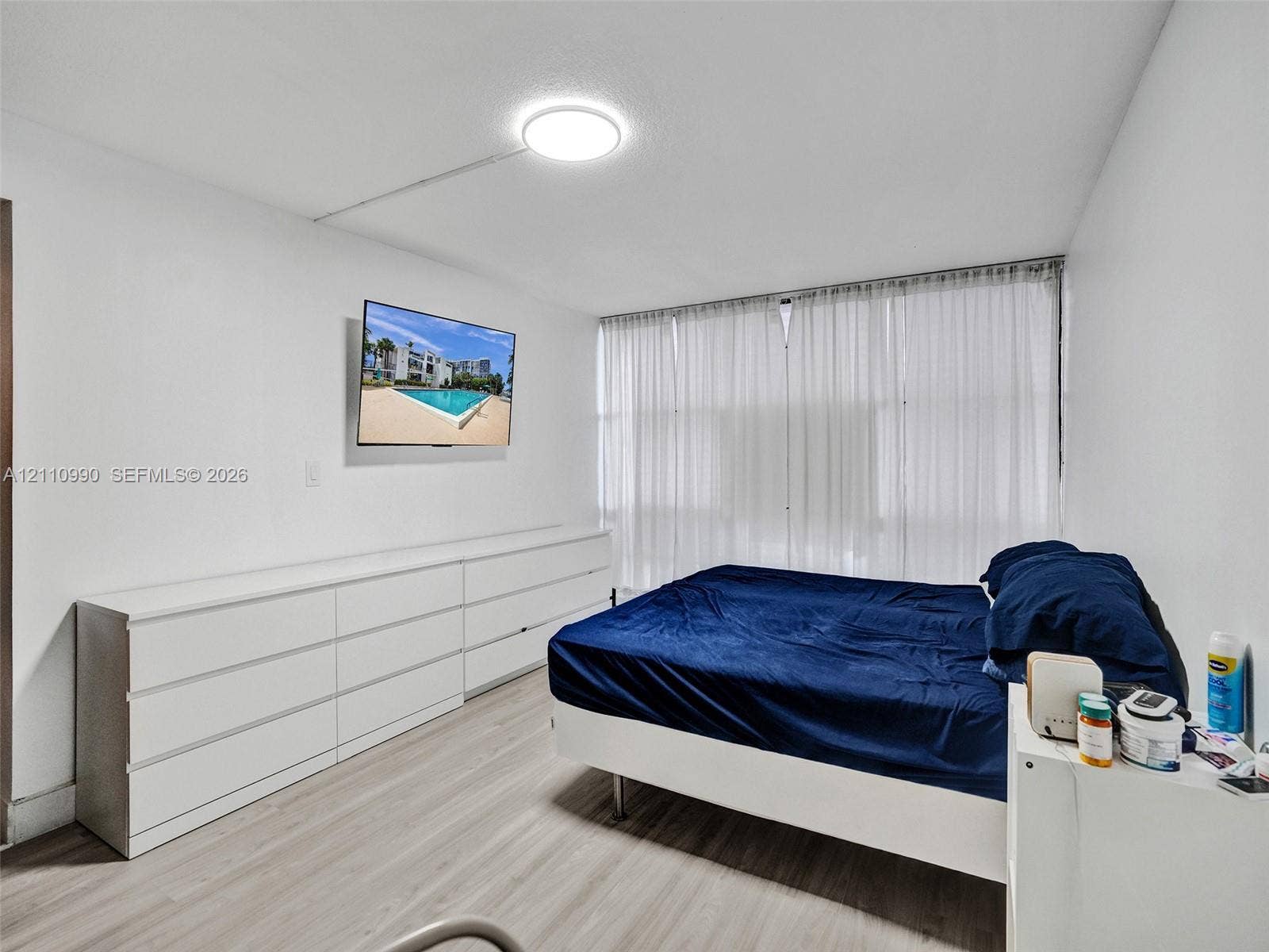 800 Parkview Drive, #131, Hallandale Beach, FL 33009 Light-toned wood-finish flooring, floor-to-ceiling sheer window treatments, and a flush-mount ceiling light fixture