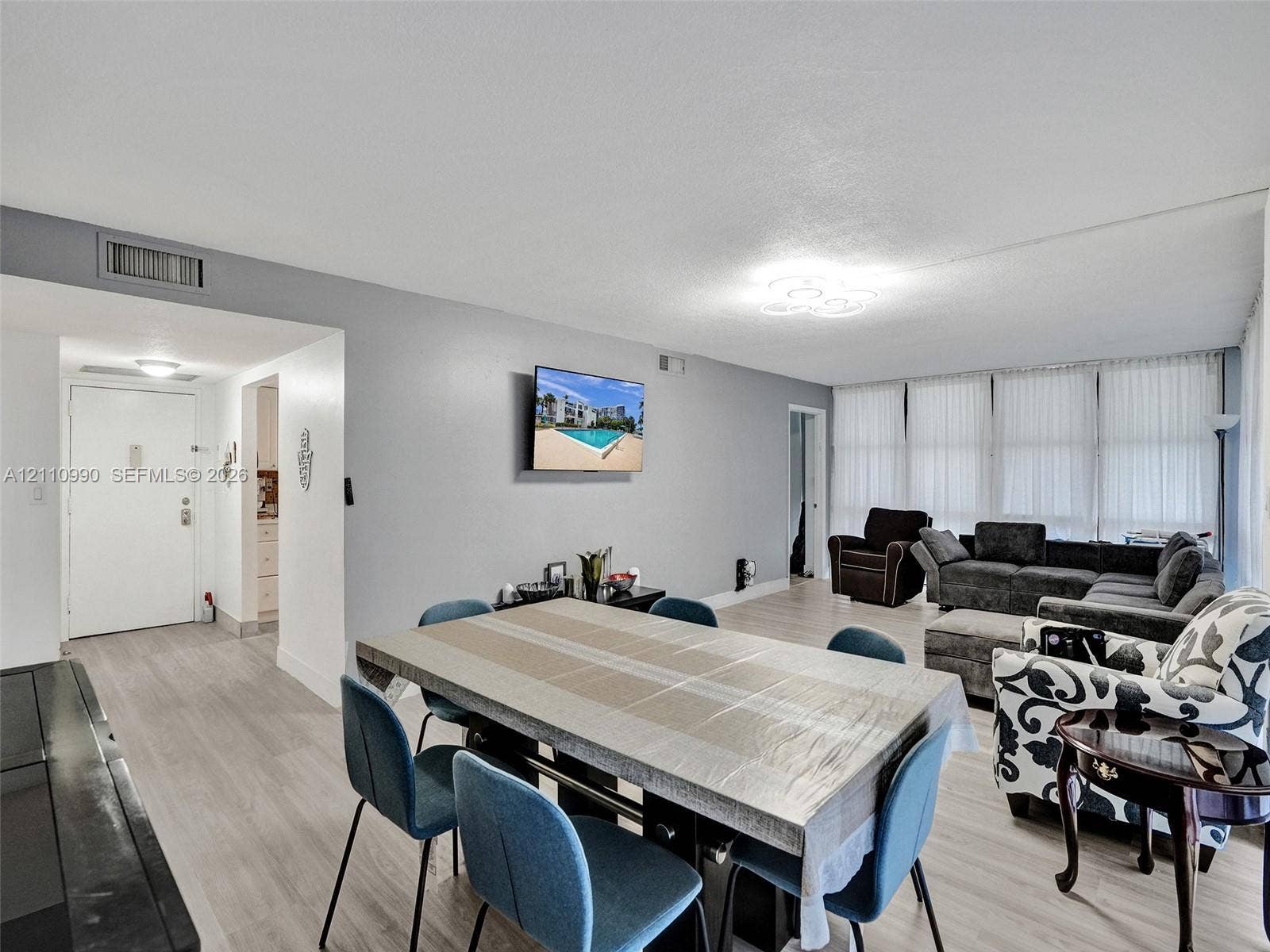 800 Parkview Drive, #131, Hallandale Beach, FL 33009 Open-concept interior featuring light wood-finish flooring, neutral wall coloring, and wall-to-wall windows with integrated vertical blinds