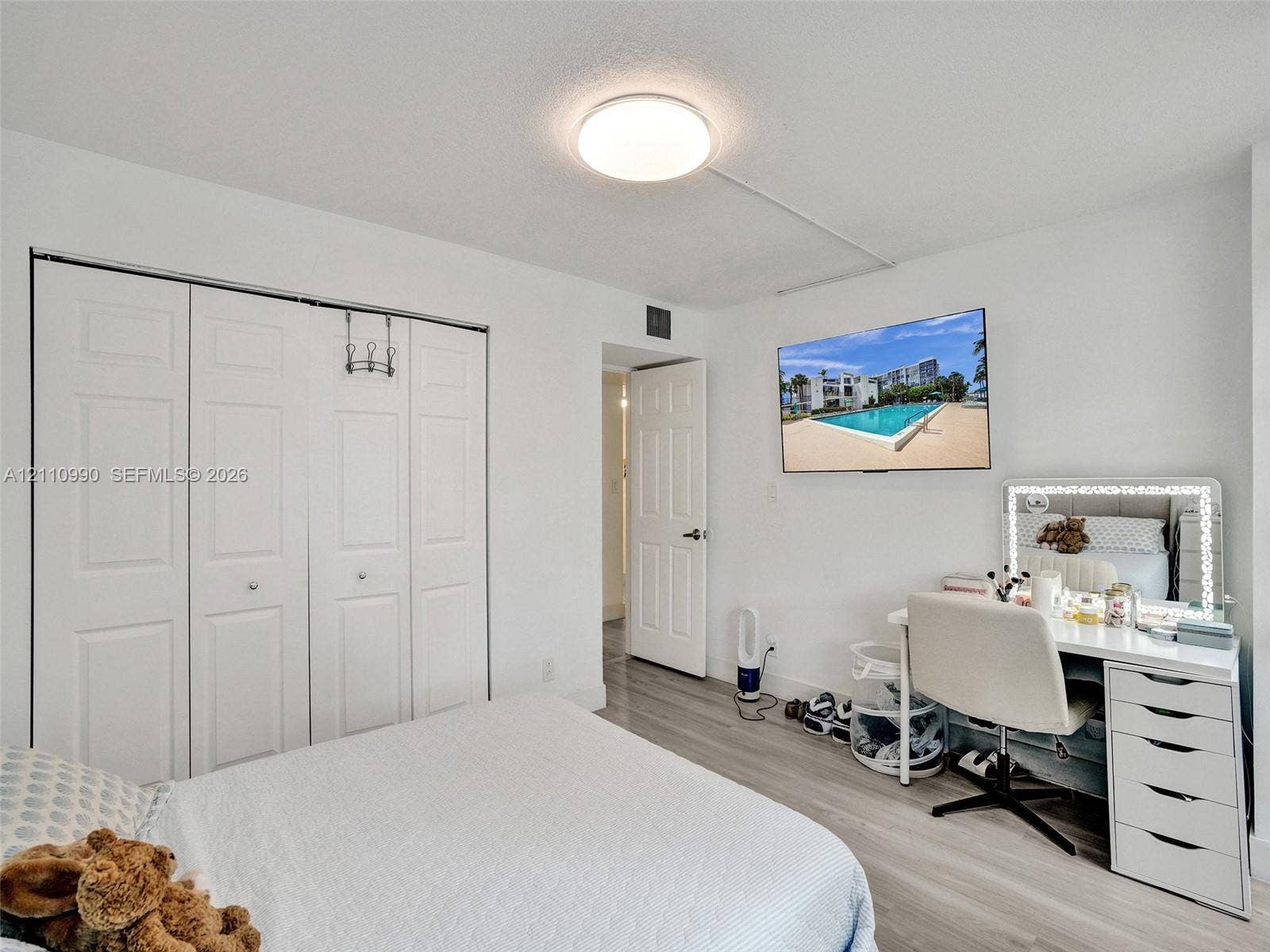 800 Parkview Drive, #131, Hallandale Beach, FL 33009 Light-filled room featuring wood-finish flooring, a wall-mounted television, and a four-panel bi-fold closet