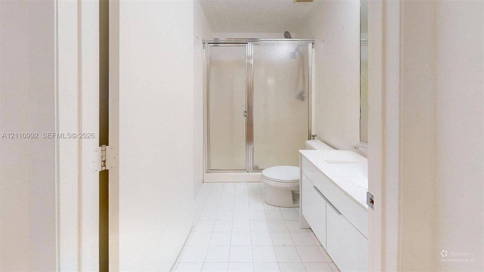 Bathroom featuring a white vanity cabinet with a stone countertop, an integrated sink, a walk-in shower with a glass enclosure, and ceramic tile flooring