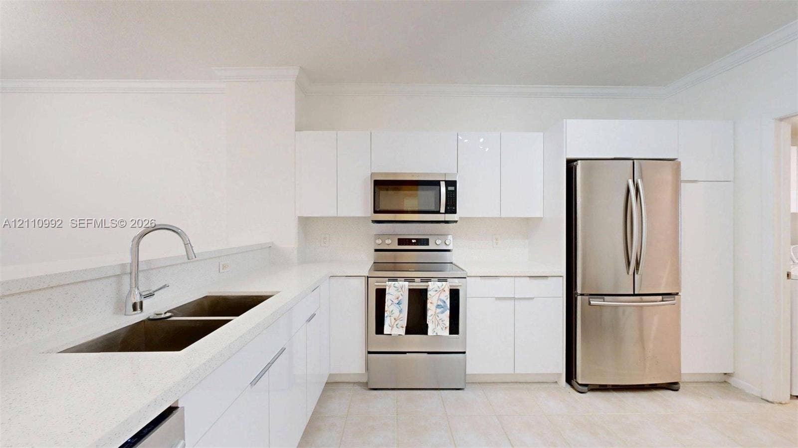 Kitchen featuring white high-gloss cabinetry, stone-finish countertops, stainless steel appliances, and a double-basin undermount sink with a gooseneck faucet