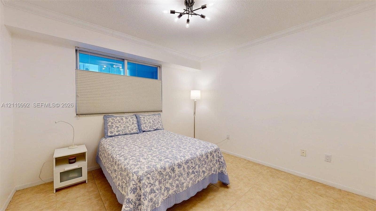 Spacious room featuring tile flooring, crown molding, and a modern multi-arm ceiling light fixture