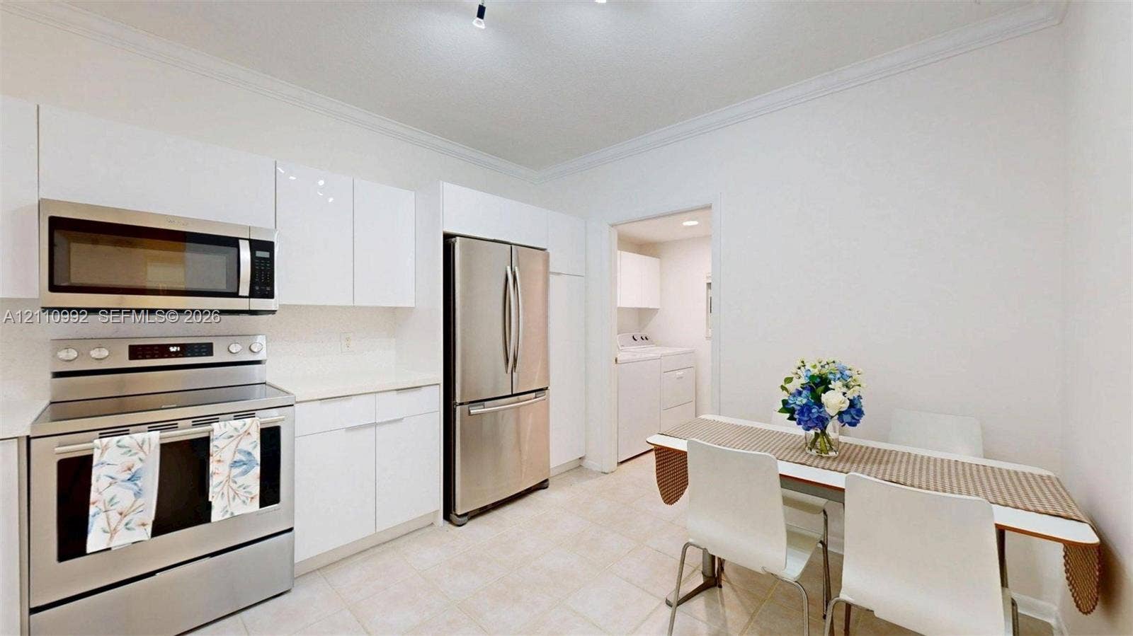 Kitchen featuring white flat-panel cabinetry, stainless steel appliances, solid surface countertops, and tile flooring