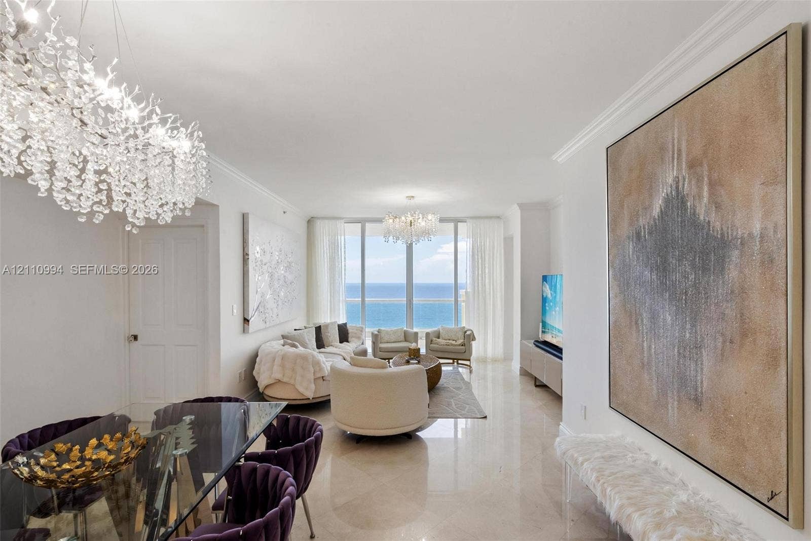 17875 Collins Avenue, #2405, Sunny Isles Beach, Sunny Isles Beach, FL 33160 Expansive living area featuring floor-to-ceiling windows with ocean scenery, polished stone flooring, recessed crown molding, and dual crystal chandeliers