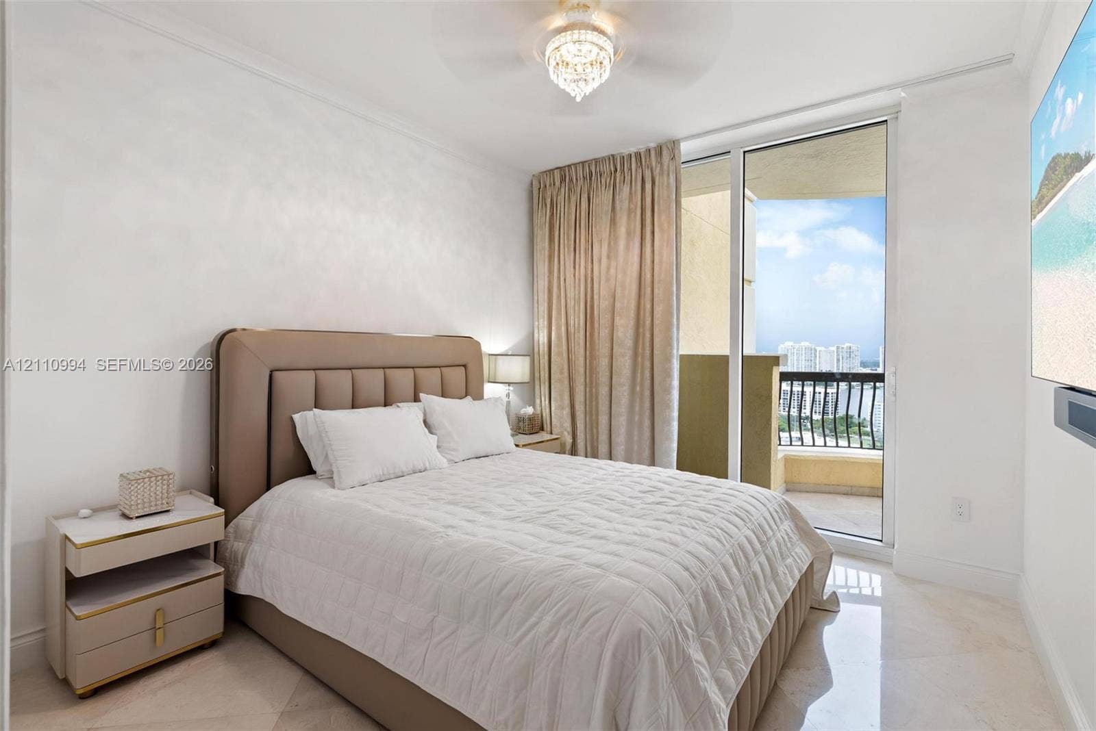 17875 Collins Avenue, #2405, Sunny Isles Beach, Sunny Isles Beach, FL 33160 Floor-to-ceiling glass sliding door with access to a balcony, polished stone flooring, and crystal-accented ceiling fan with light fixture