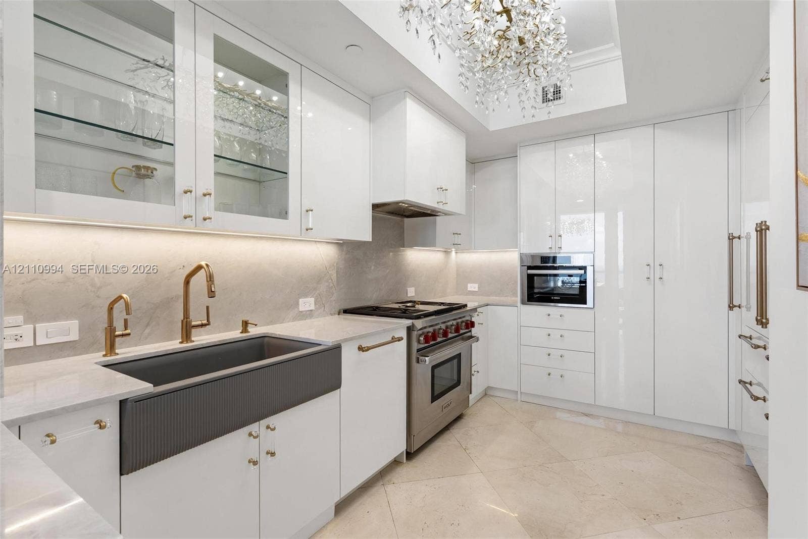17875 Collins Avenue, #2405, Sunny Isles Beach, Sunny Isles Beach, FL 33160 Kitchen featuring high-gloss cabinetry, stone-finish countertops, a dark-toned apron-front sink with gold-tone fixtures, stainless steel professional-grade range, and integrated appliances