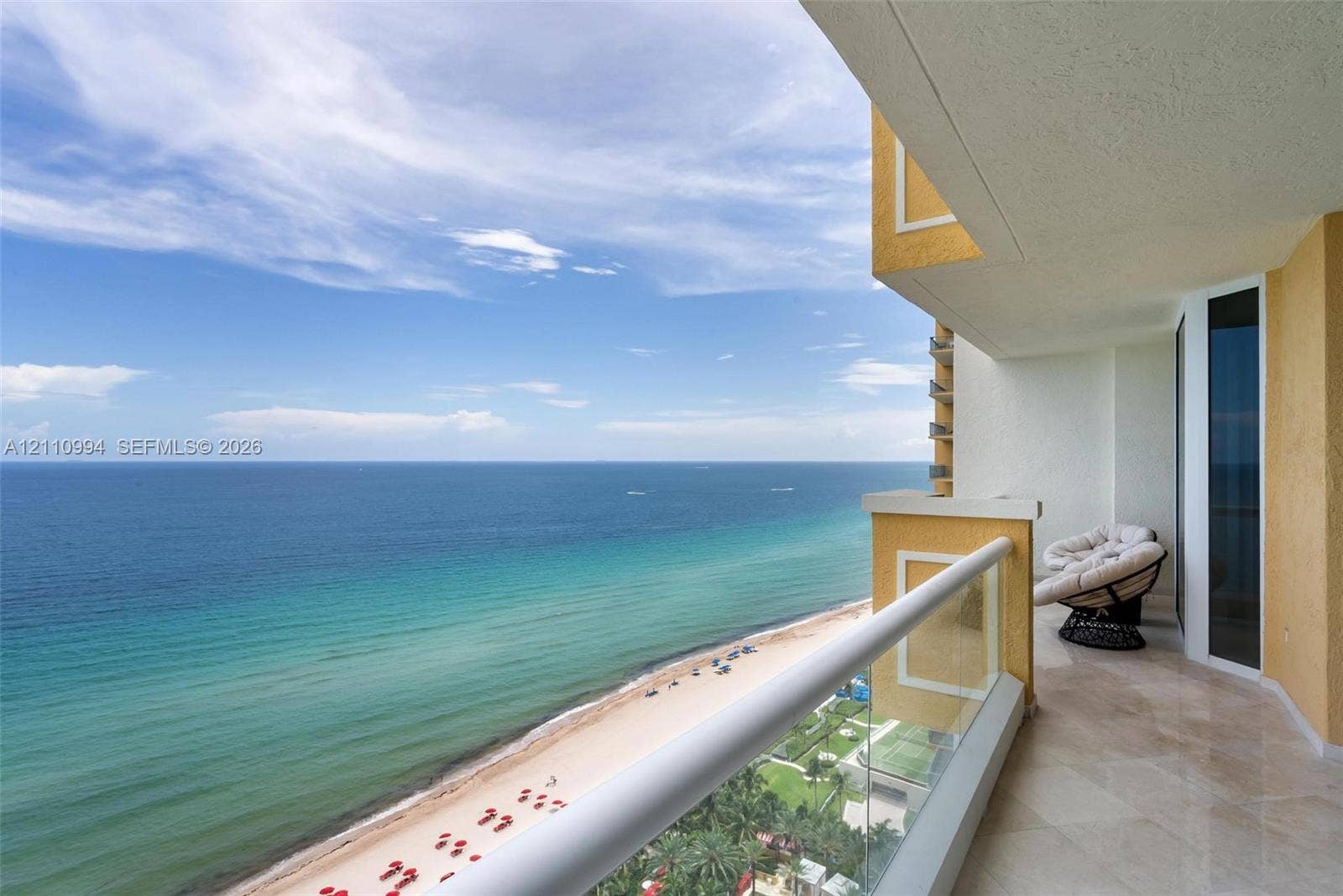 17875 Collins Avenue, #2405, Sunny Isles Beach, Sunny Isles Beach, FL 33160 Covered balcony featuring natural stone flooring, glass railing, and textured exterior wall finish, overlooking the coastline