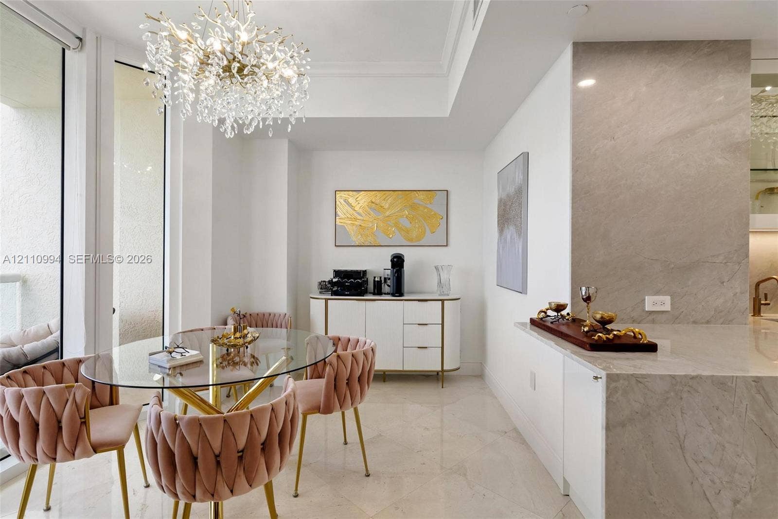 17875 Collins Avenue, #2405, Sunny Isles Beach, Sunny Isles Beach, FL 33160 Large-format stone tile flooring, statement crystal chandelier, neutral-tone stone slab countertop, and floor-to-ceiling glass panel door