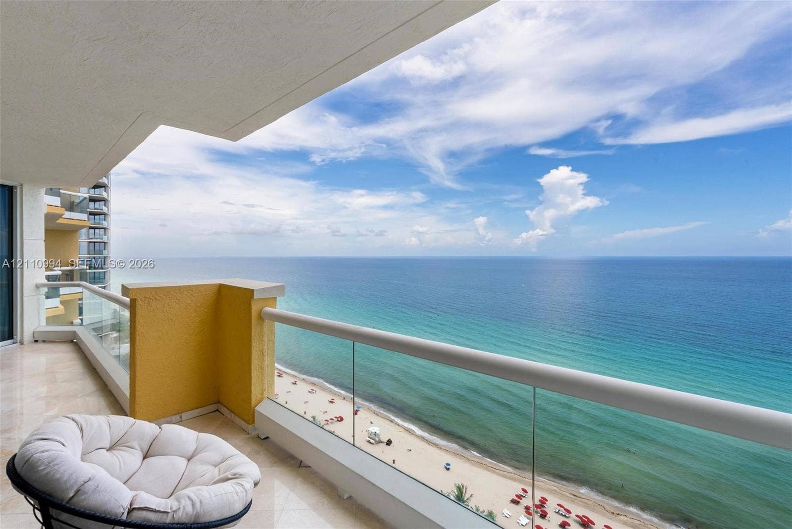 17875 Collins Avenue, #2405, Sunny Isles Beach, Sunny Isles Beach, FL 33160 Covered balcony featuring polished stone flooring, glass panel railings, and expansive oceanfront scenery