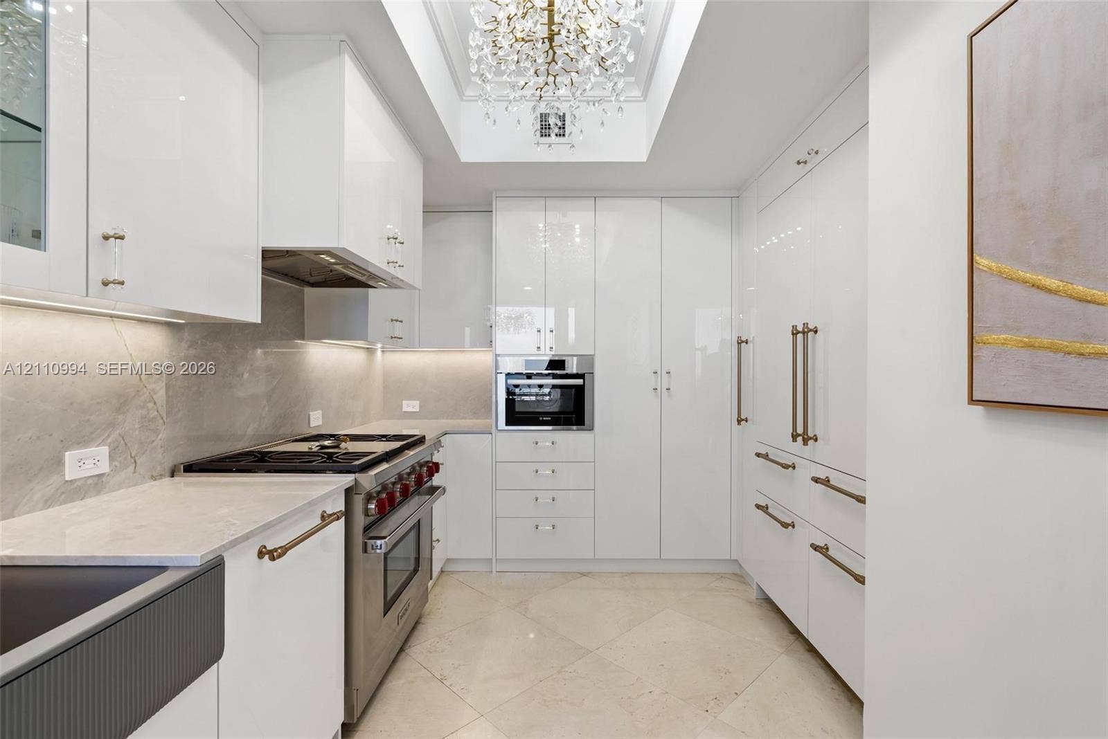 17875 Collins Avenue, #2405, Sunny Isles Beach, Sunny Isles Beach, FL 33160 Gourmet kitchen featuring high-gloss cabinetry, stone-finish countertops, tile flooring, stainless steel professional-grade range, and a coffered ceiling with crystal chandelier