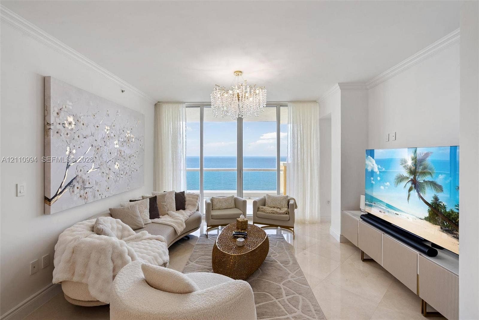 17875 Collins Avenue, #2405, Sunny Isles Beach, Sunny Isles Beach, FL 33160 Living space featuring polished stone flooring, crown molding, a crystal chandelier, floor-to-ceiling glass wall, and direct ocean backdrop