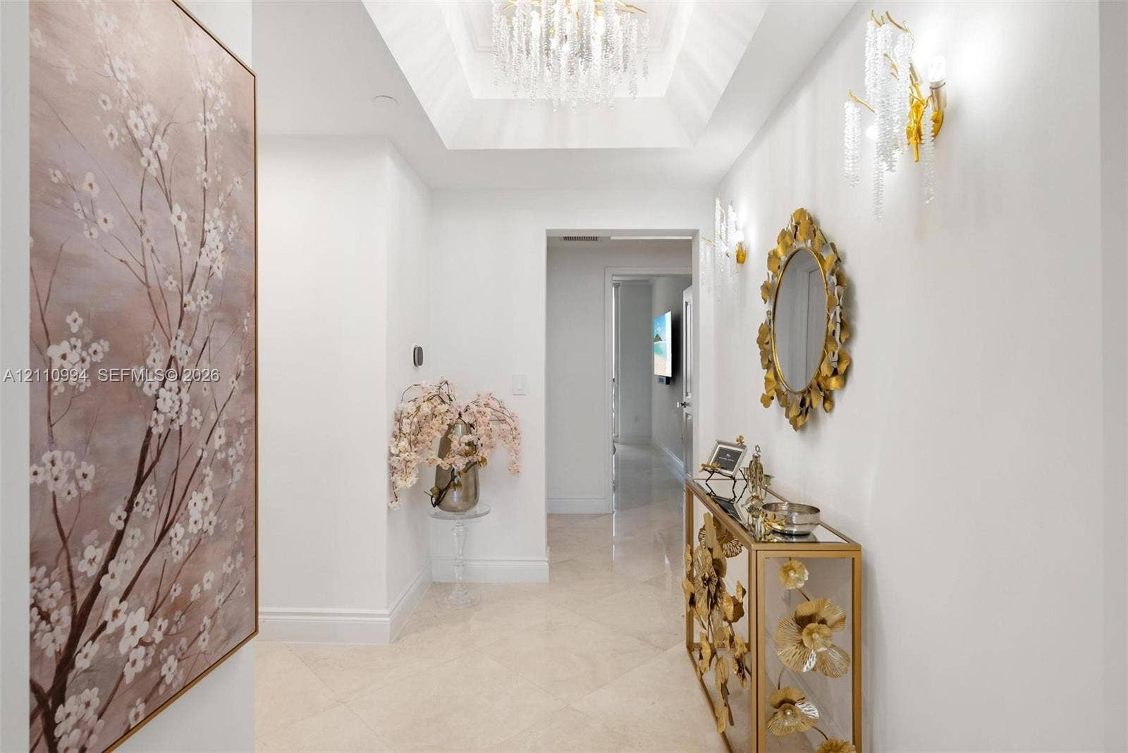 17875 Collins Avenue, #2405, Sunny Isles Beach, Sunny Isles Beach, FL 33160 Foyer featuring a recessed tray ceiling, tiered crystal chandelier, wall-mounted crystal sconces, and neutral stone-finish flooring