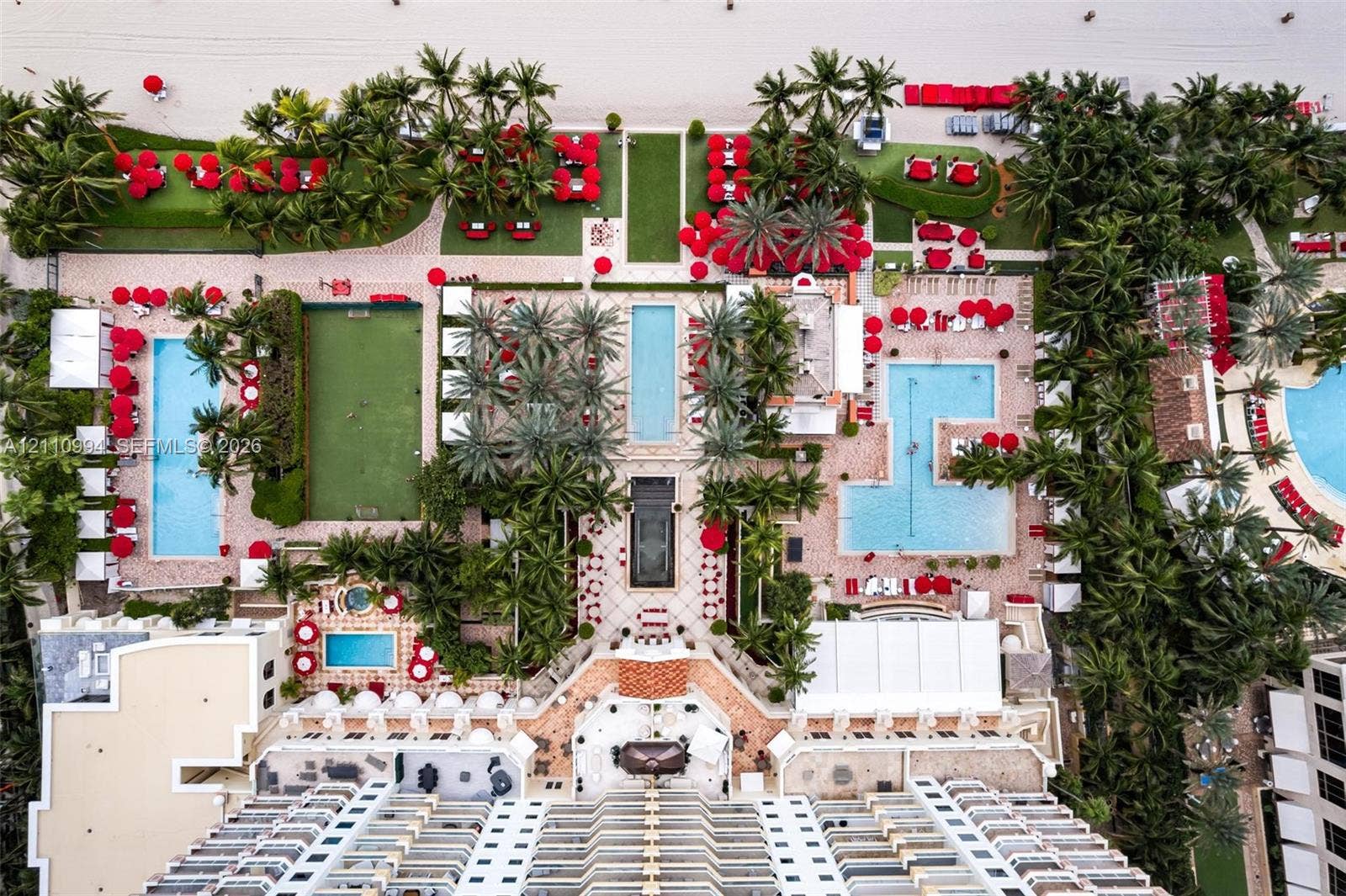 17875 Collins Avenue, #2405, Sunny Isles Beach, Sunny Isles Beach, FL 33160 Aerial perspective featuring multi-level swimming pools, manicured palm landscaping, private putting green, and stone-paved courtyards with direct beach access