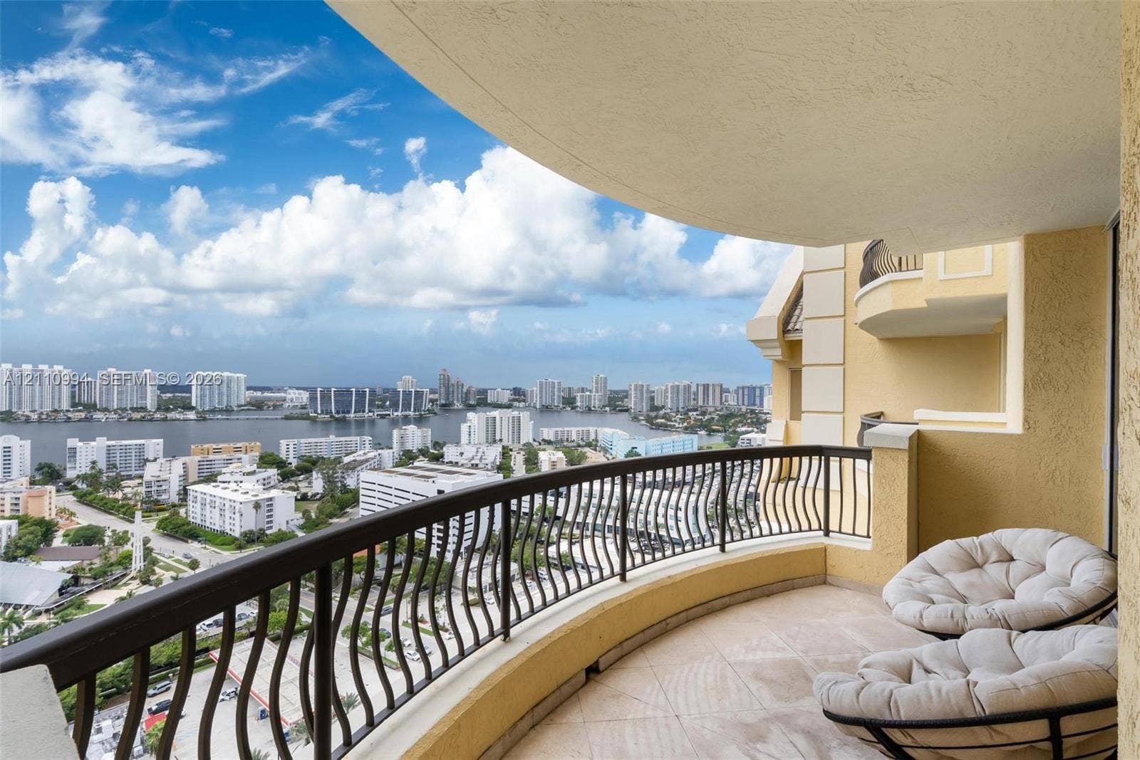 17875 Collins Avenue, #2405, Sunny Isles Beach, Sunny Isles Beach, FL 33160 Covered balcony featuring tile flooring and a decorative metal railing overlooking the surrounding urban and waterfront landscape