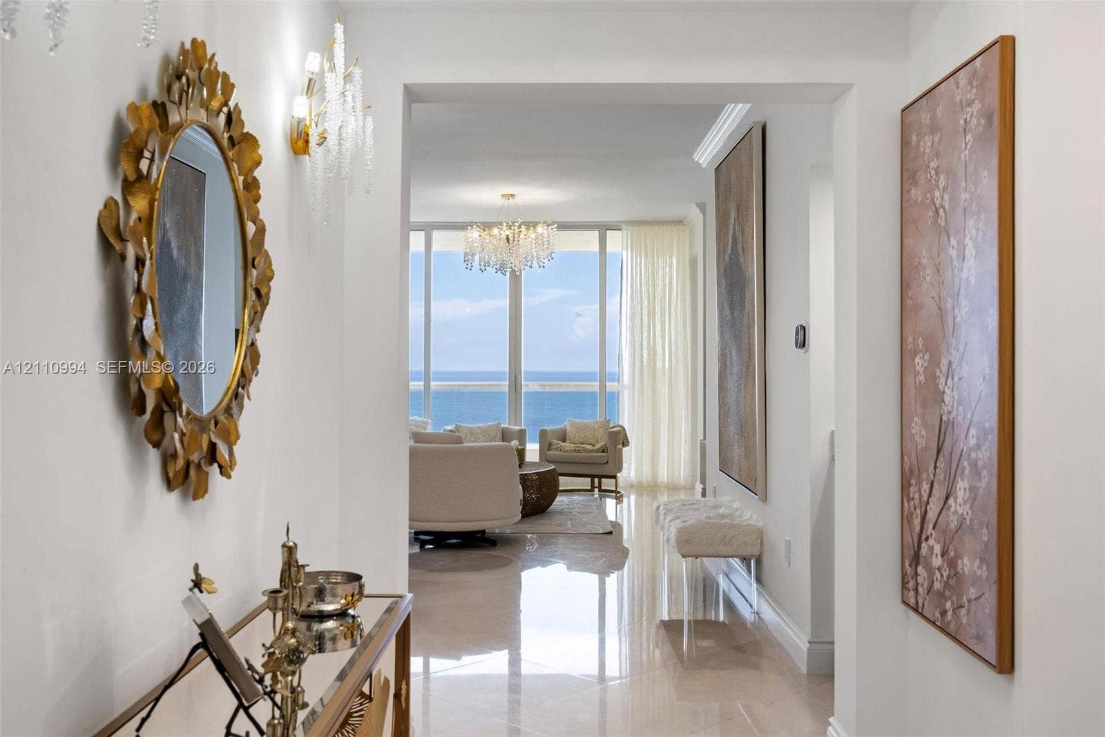 17875 Collins Avenue, #2405, Sunny Isles Beach, Sunny Isles Beach, FL 33160 Entryway featuring polished stone-finish flooring, crown molding, and crystal wall-mounted light fixtures, leading to floor-to-ceiling windows with ocean scenery