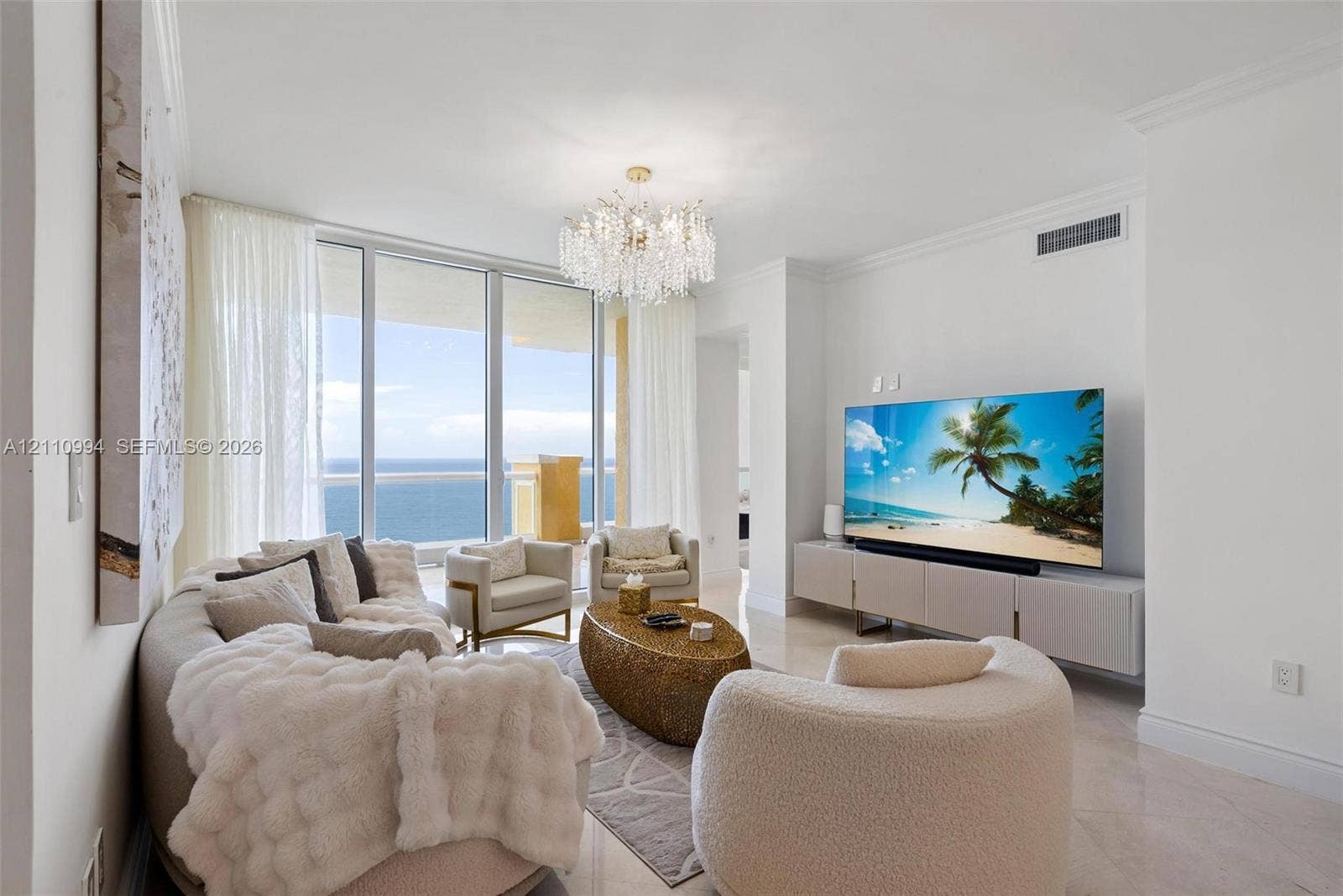 17875 Collins Avenue, #2405, Sunny Isles Beach, Sunny Isles Beach, FL 33160 Living space featuring floor-to-ceiling glass panel doors, polished stone flooring, a multi-tiered crystal chandelier, and crown molding