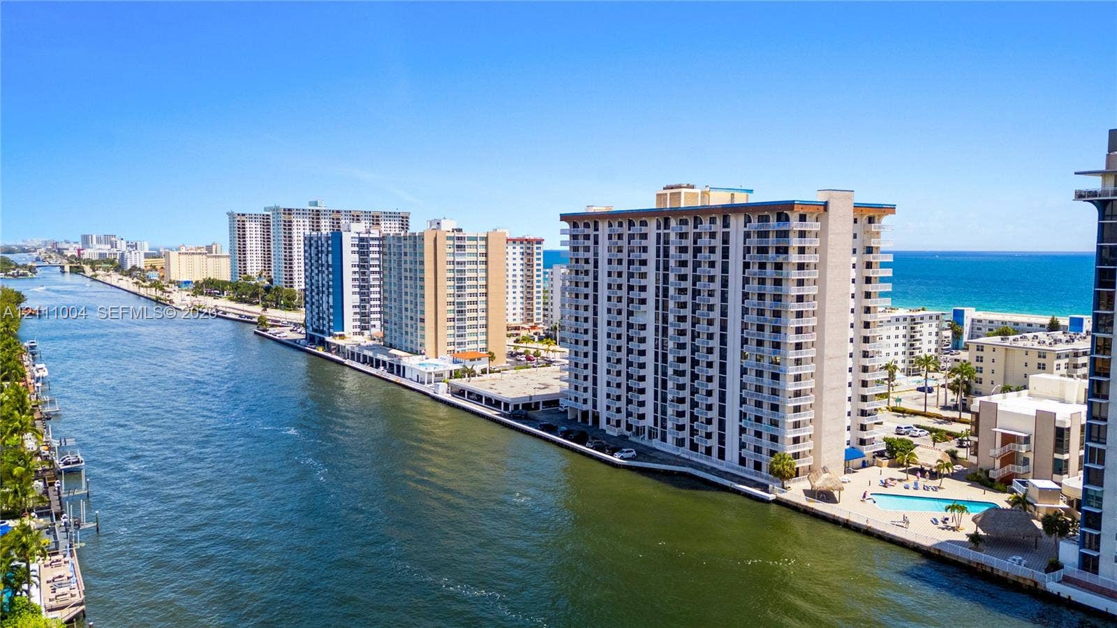 Waterfront high-rise building featuring balconies, an outdoor swimming pool, and direct canal frontage with proximity to the ocean