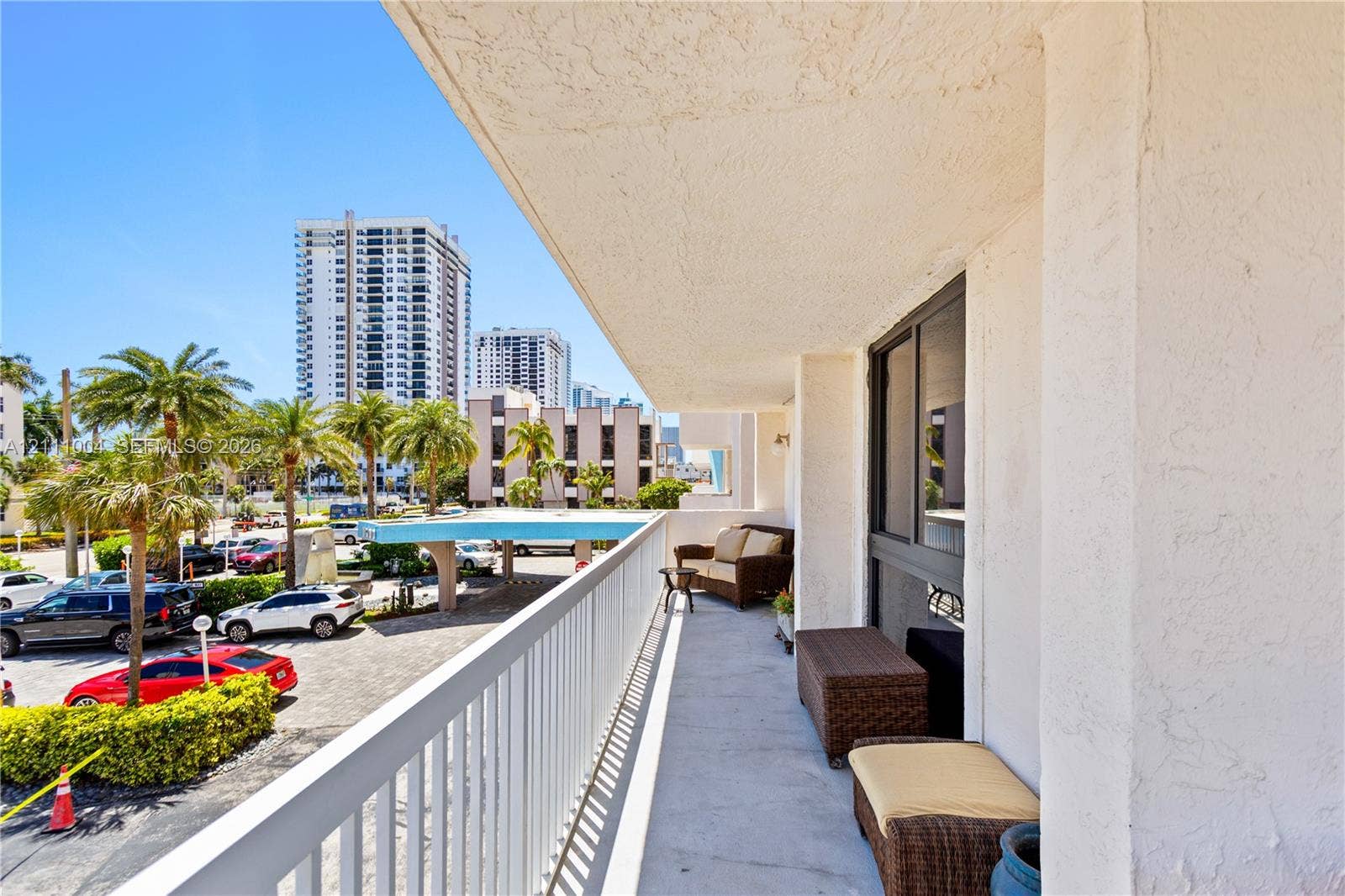 Covered balcony with a concrete floor, white metal railing, and glass sliding door access