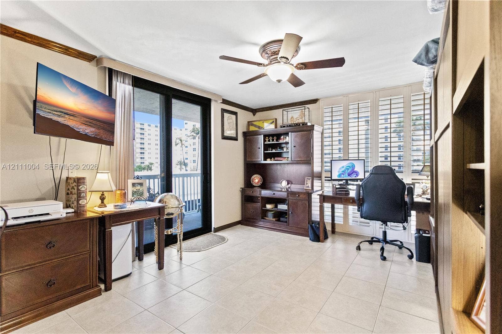 Tile flooring, plantation shutters, built-in wooden cabinetry, ceiling fan, and sliding glass door