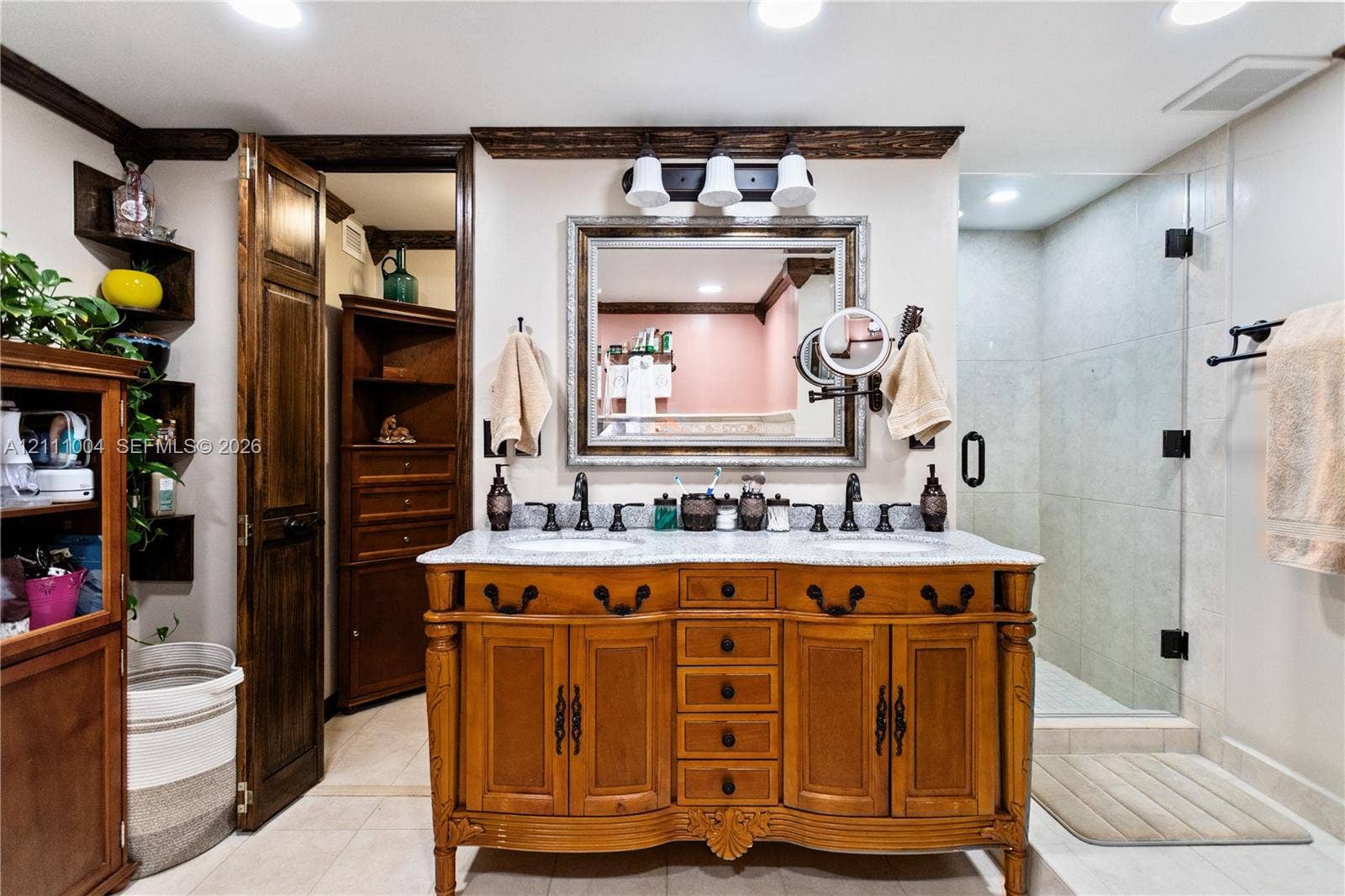 Double vanity featuring a stained-wood cabinet base, stone-surface countertop, dual drop-in sinks, and a framed vanity mirror
