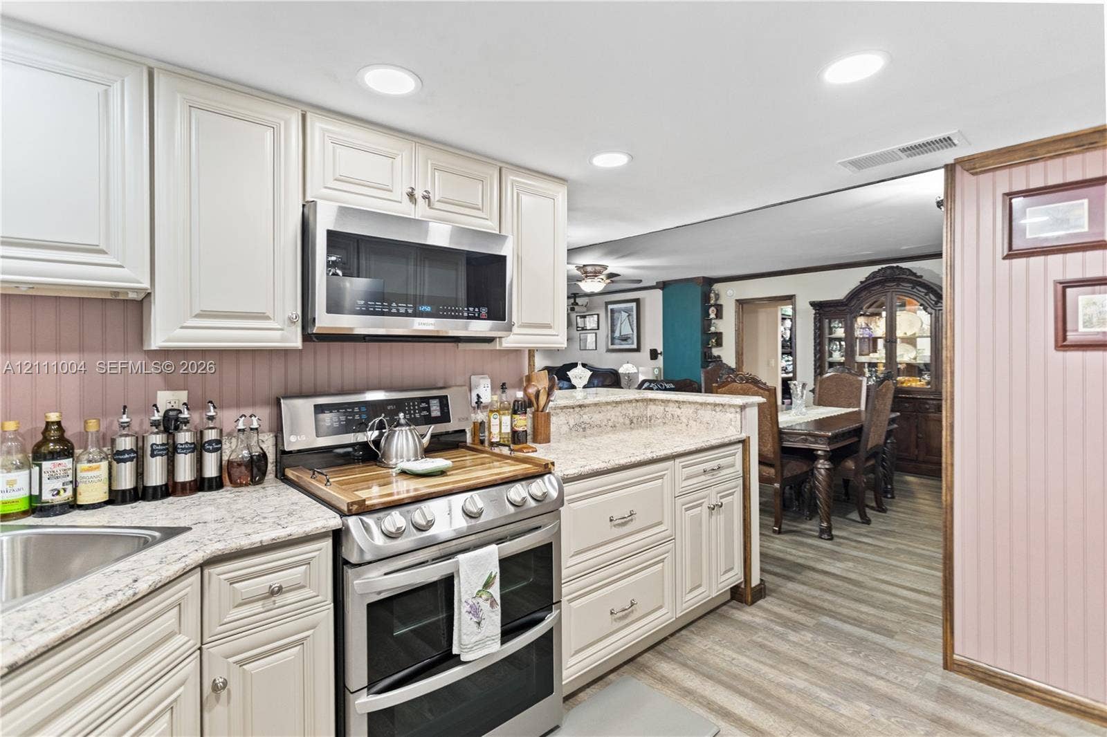 Kitchen featuring off-white cabinetry, stone-finish countertops, stainless steel appliances, recessed lighting, and wood-finish flooring
