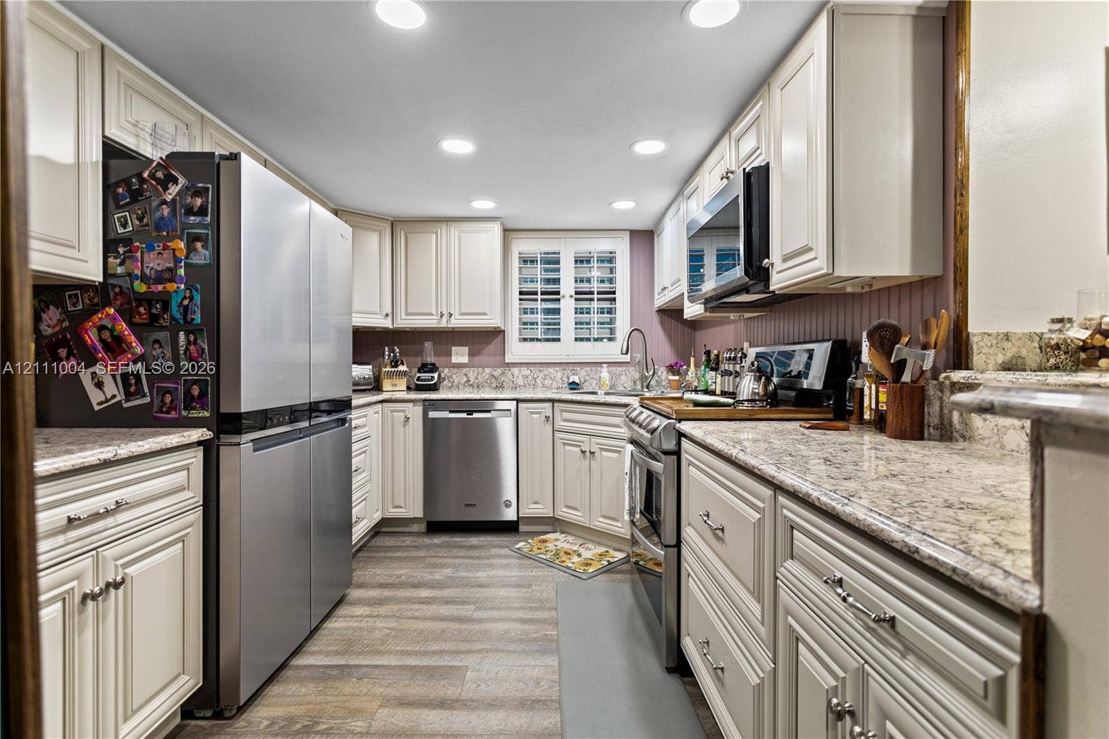 Kitchen featuring shaker-style cabinetry, stone countertops, stainless steel appliances, recessed lighting, and wood-finish flooring