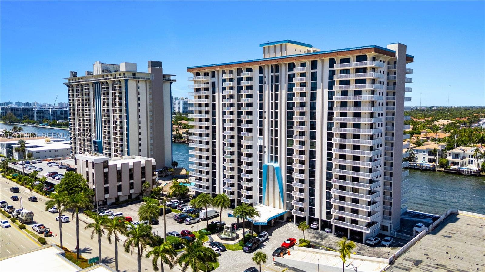 High-rise residential exterior featuring private balconies, waterfront placement, and mature palm landscaping