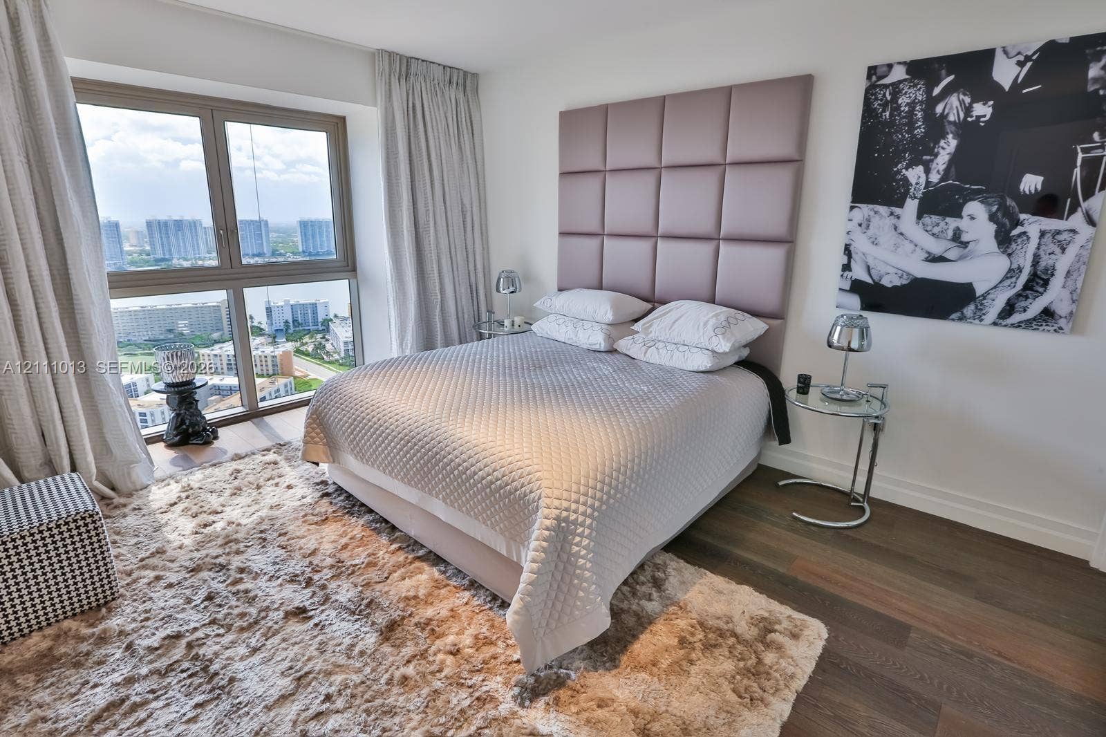 Floor-to-ceiling window featuring expansive outdoor scenery, wood-finish flooring, and a built-in wall-mounted padded headboard