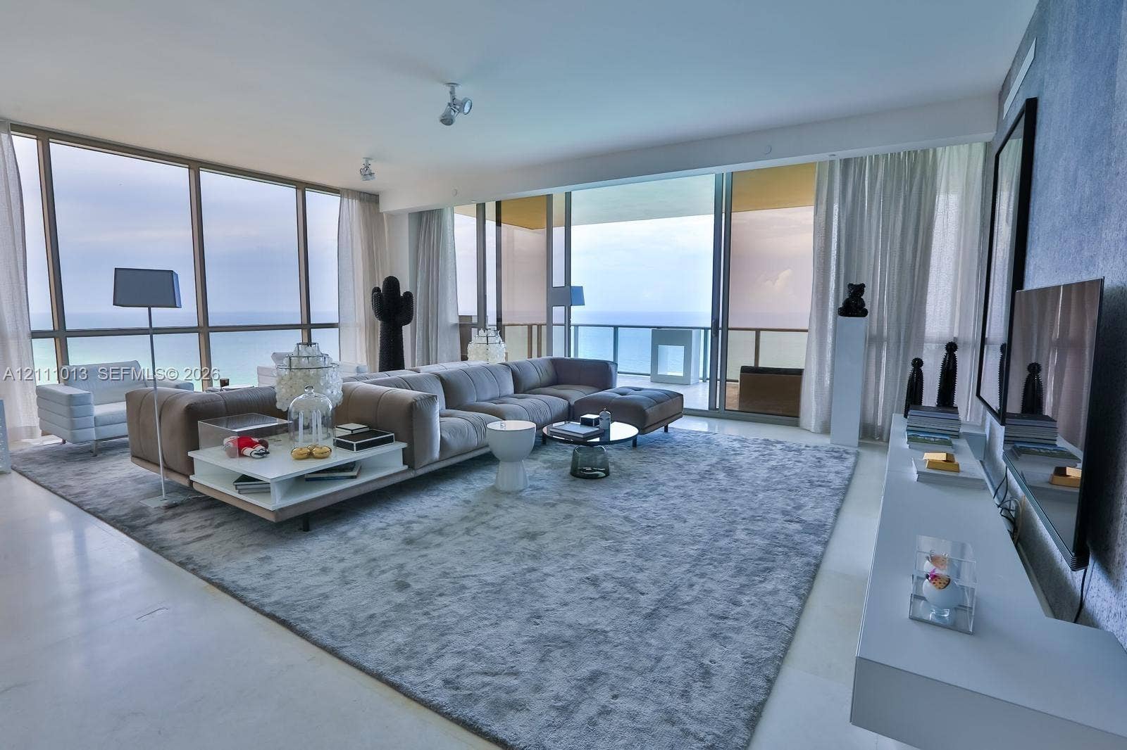 Floor-to-ceiling glass walls, expansive private balcony, stone flooring, and built-in wall-mounted cabinetry