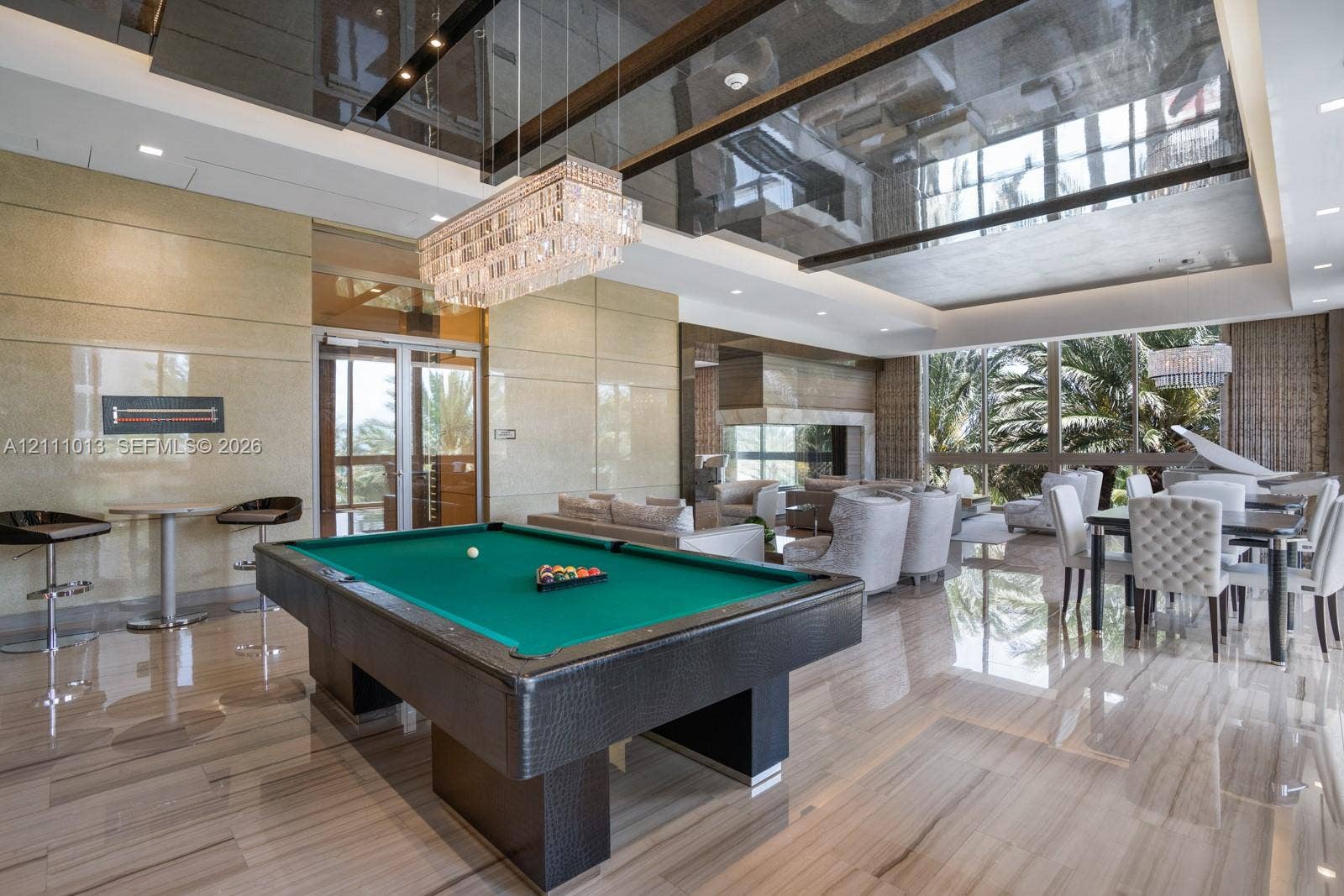 Expansive interior featuring high-gloss tile flooring, reflective tray ceilings, oversized floor-to-ceiling windows, and a multi-tiered crystal chandelier
