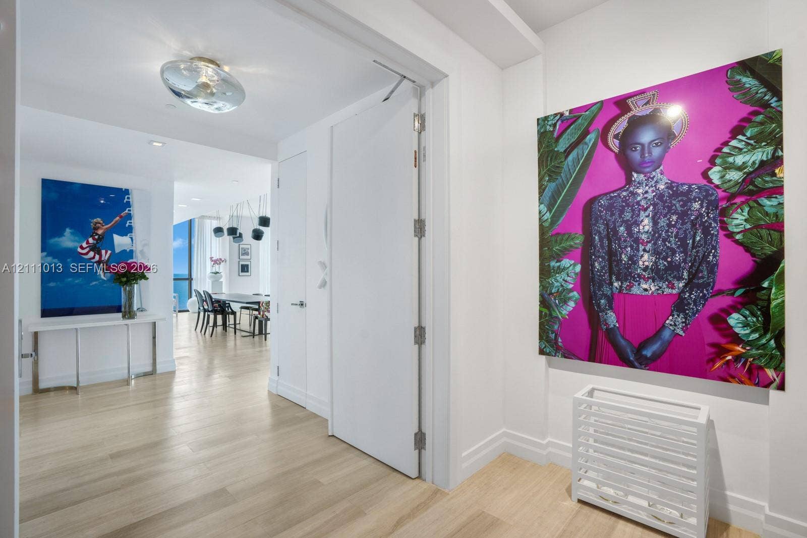 Interior hallway featuring wood-finish flooring, smooth-finish walls, ceiling-mounted circular lighting, and a full-height interior door with metal hinges