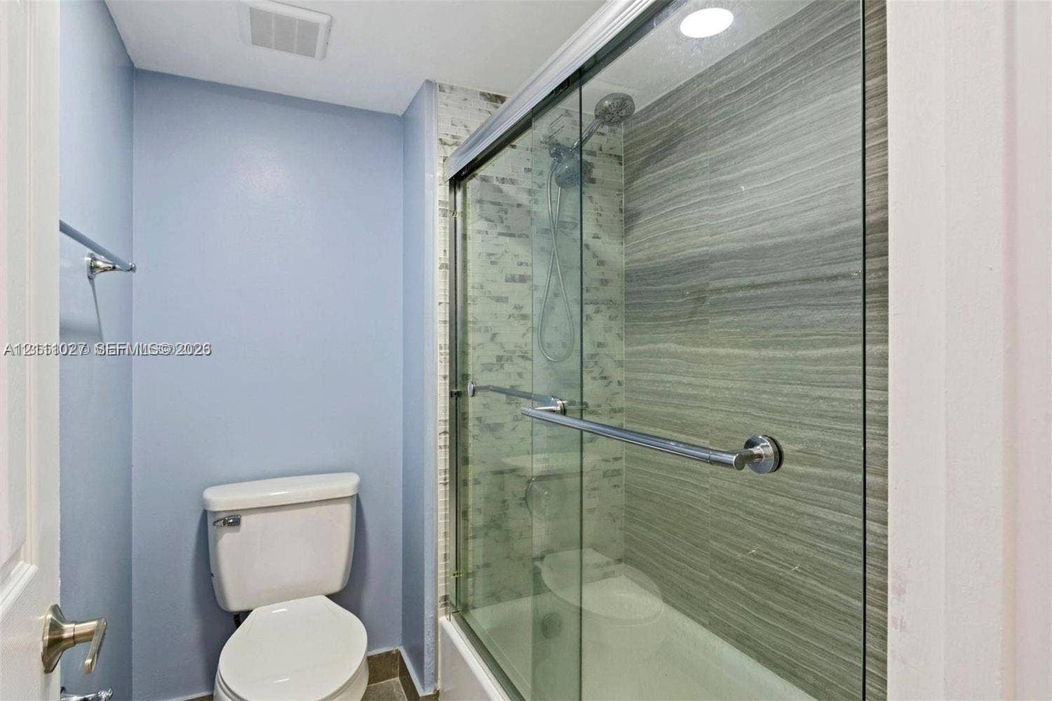 Shower enclosure with sliding glass doors, horizontal tile wall surfacing, overhead rain-style showerhead, and integrated bathtub