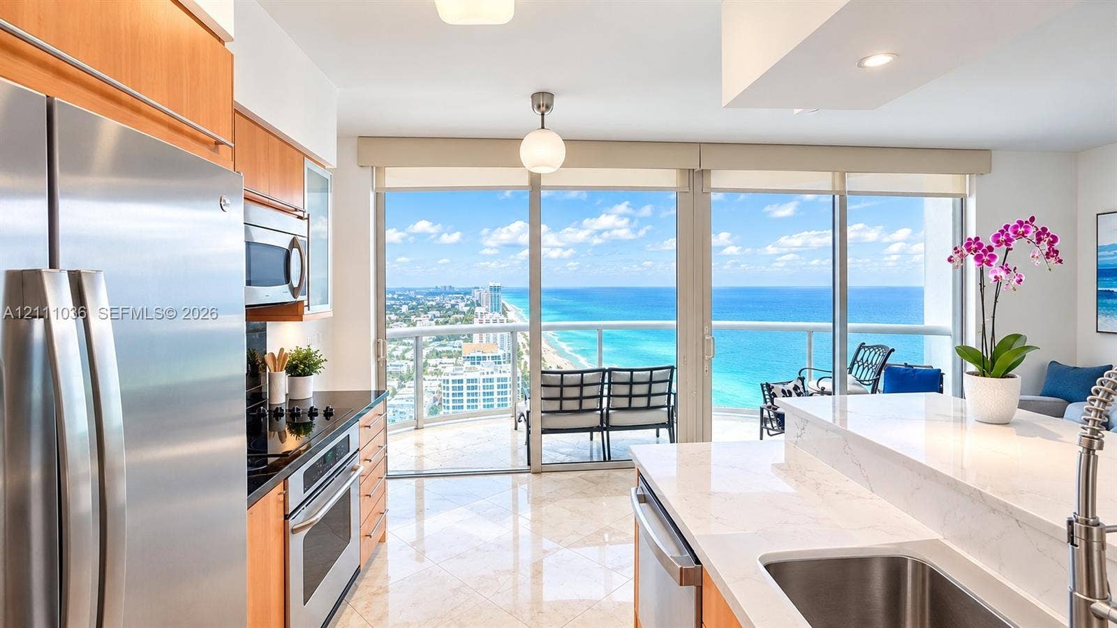 6365 Collins Avenue, #3811, Miami Beach, FL 33141 Kitchen featuring light-finish cabinetry, stone countertops, stainless steel appliances, polished tile flooring, and floor-to-ceiling glass doors opening to a balcony