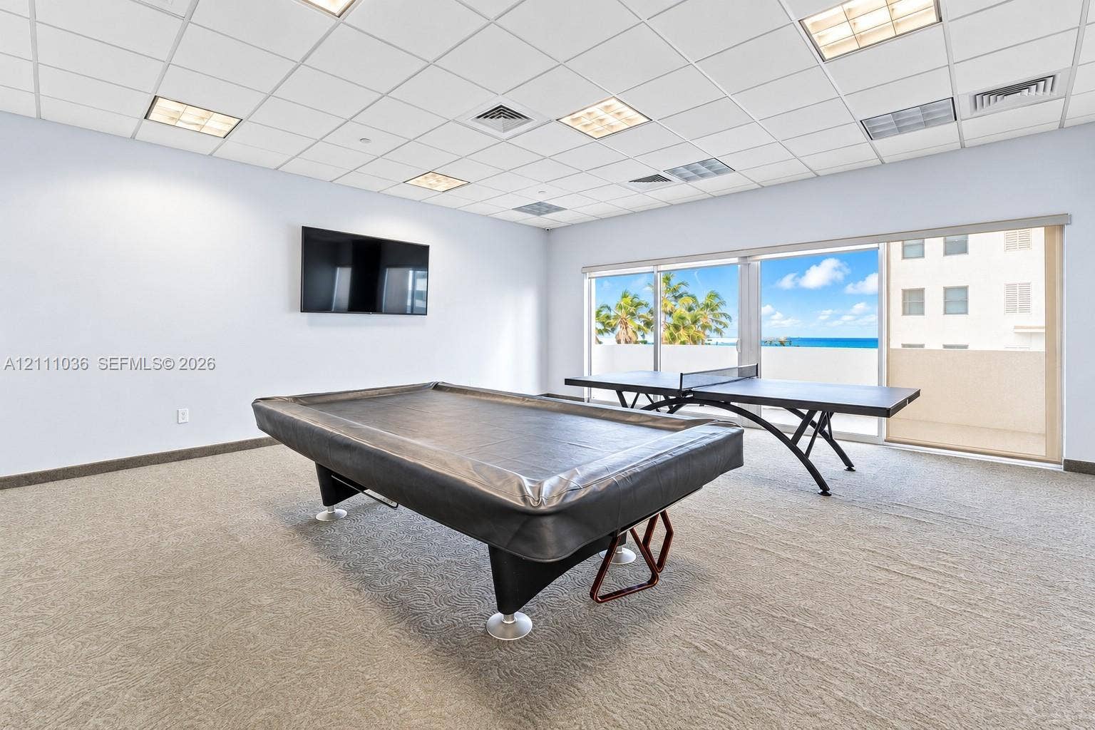 6365 Collins Avenue, #3811, Miami Beach, FL 33141 Spacious room featuring wall-to-wall carpeting, recessed ceiling grid lighting, and sliding glass doors opening to a balcony with water exposure