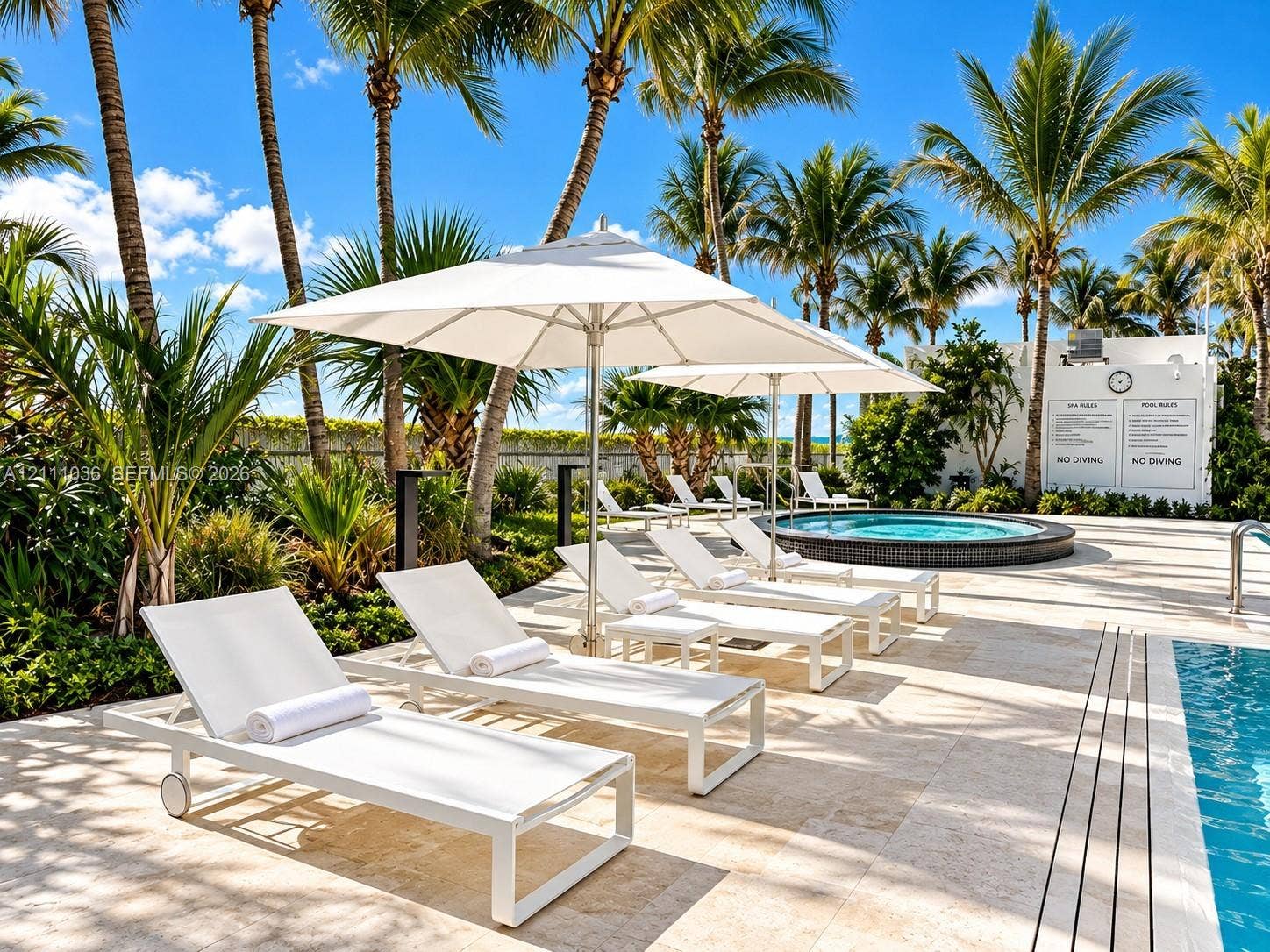 6365 Collins Avenue, #3811, Miami Beach, FL 33141 Outdoor pool area featuring natural stone decking, a circular jetted spa, and mature palm landscaping