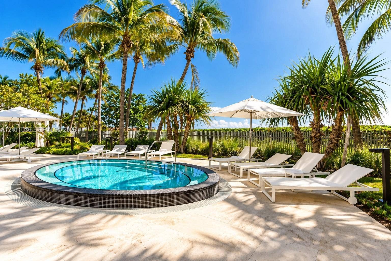6365 Collins Avenue, #3811, Miami Beach, FL 33141 Circular swimming pool with dark tile surround, light-toned stone decking, and mature palm landscaping