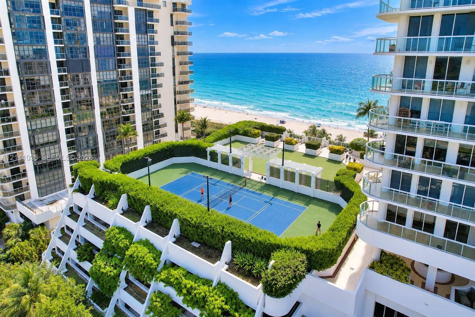6365 Collins Avenue, #3811, Miami Beach, FL 33141 Rooftop recreational level featuring a tennis court, synthetic grass lawn area, perimeter hedge landscaping, and white pergola structures