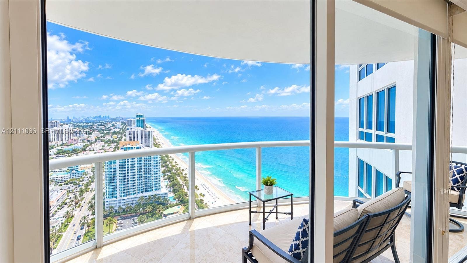 6365 Collins Avenue, #3811, Miami Beach, FL 33141 Covered wrap-around balcony featuring glass panel railings, stone flooring, and expansive coastal and urban scenery