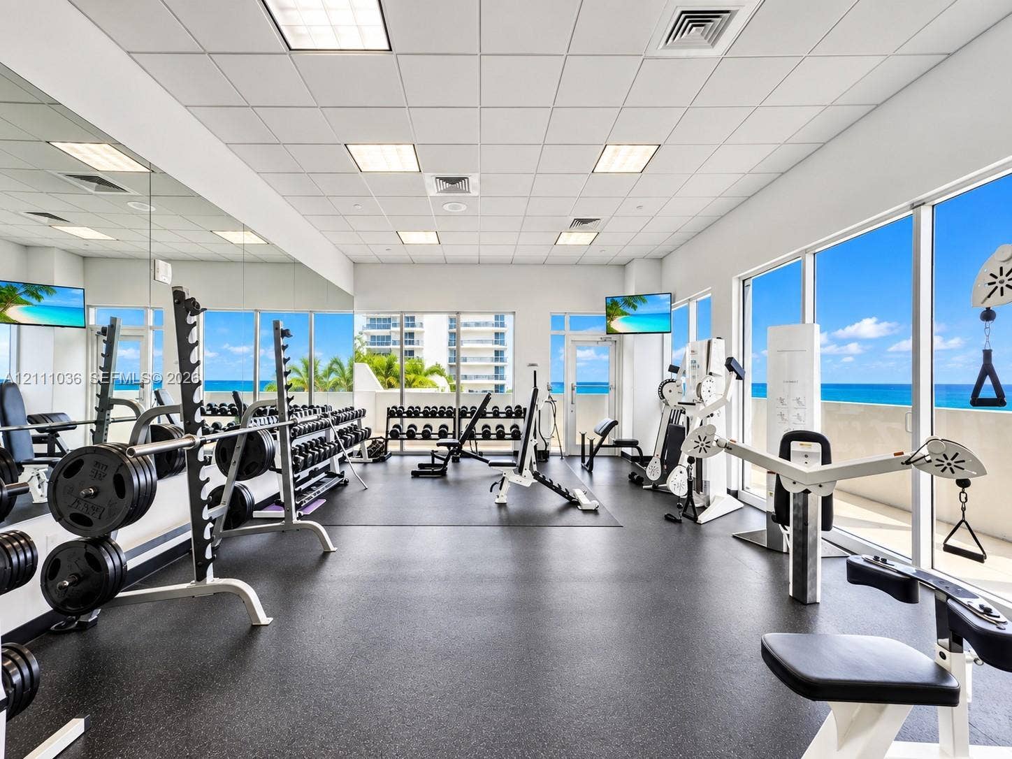 6365 Collins Avenue, #3811, Miami Beach, FL 33141 Fitness center featuring floor-to-ceiling windows, full-wall mirrors, rubberized flooring, and drop-ceiling tiles