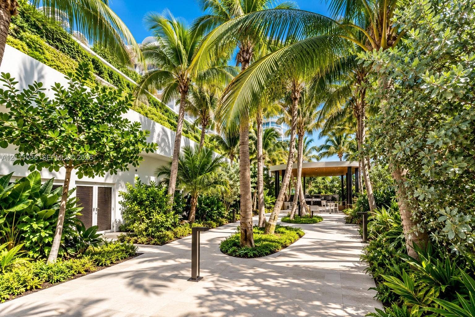6365 Collins Avenue, #3811, Miami Beach, FL 33141 Landscaped courtyard featuring stone paving, mature palm trees, integrated green walls, and a covered pavilion